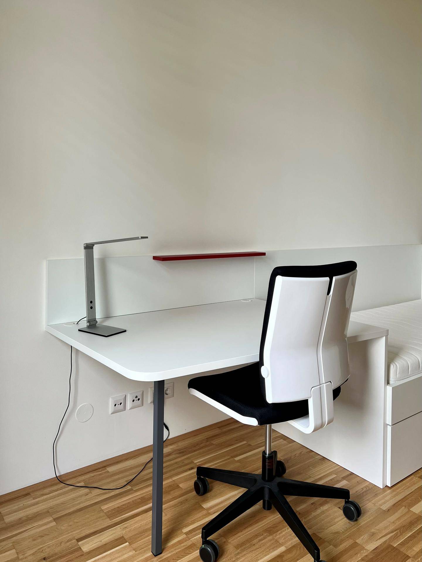 Detailansicht eines modernen Schreibtisches mit Bürostuhl und integrierter Beleuchtung im Schlafzimmer.