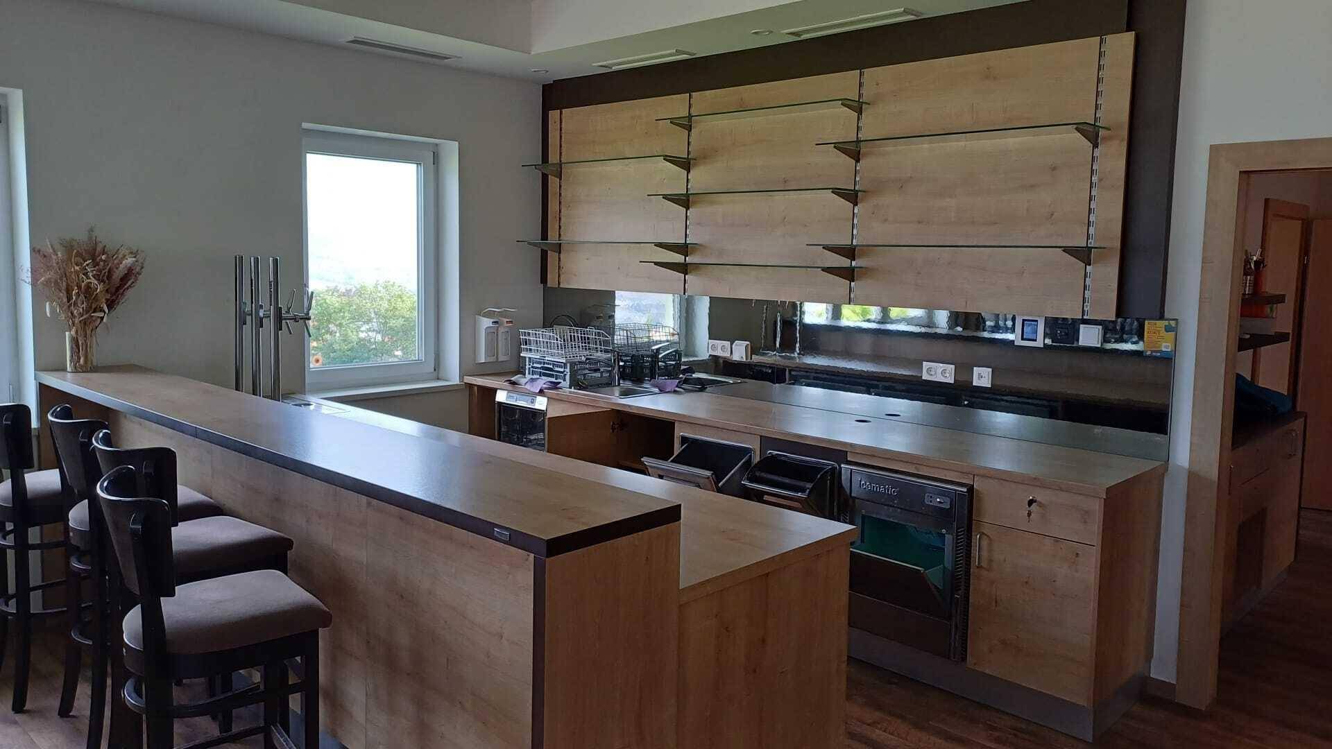 Moderne Bar mit Holztheke, Glasregalen und Blick aus dem Fenster auf die Umgebung.