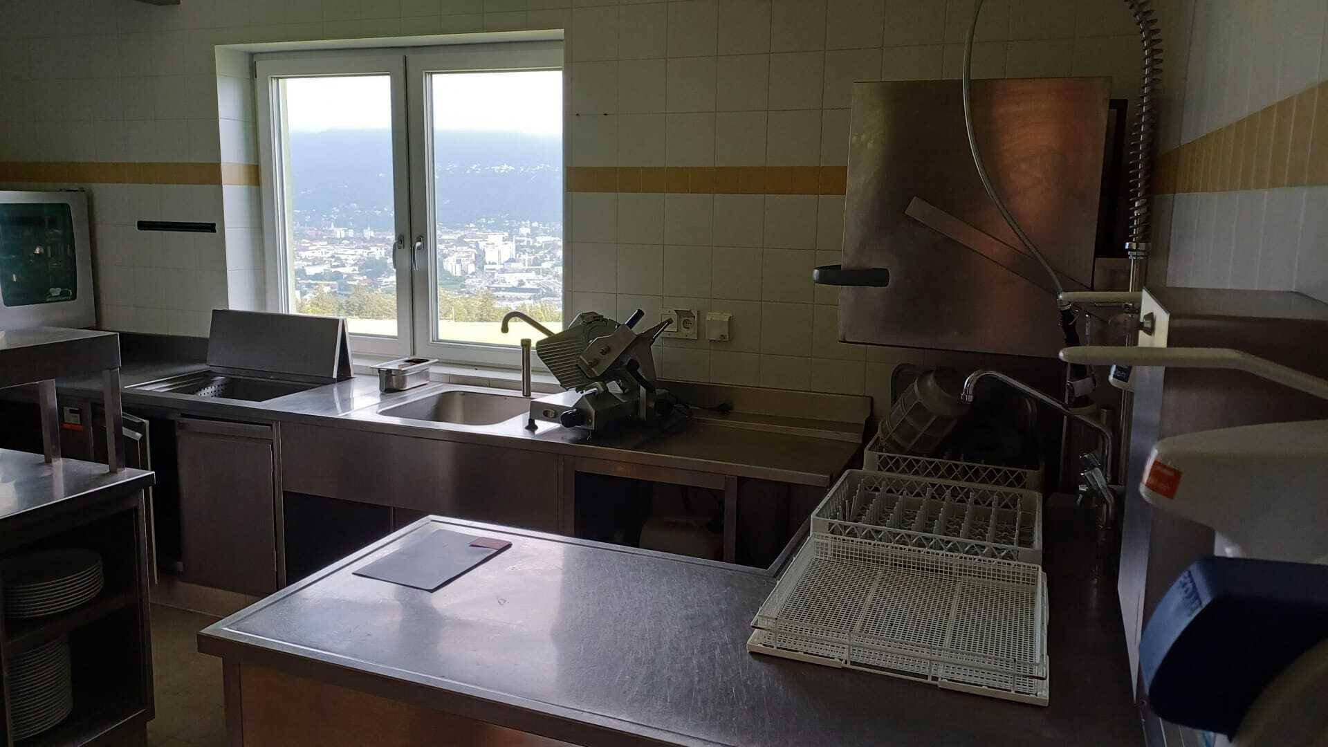 Professionelle Edelstahlküche mit Spülbecken, Arbeitsflächen und Blick aus dem Fenster auf die Stadt.