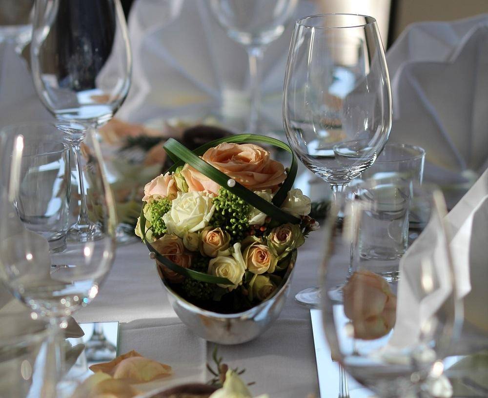 Nahaufnahme einer eleganten Tischdekoration mit frischen Blumen und Weingläsern für eine Feier.