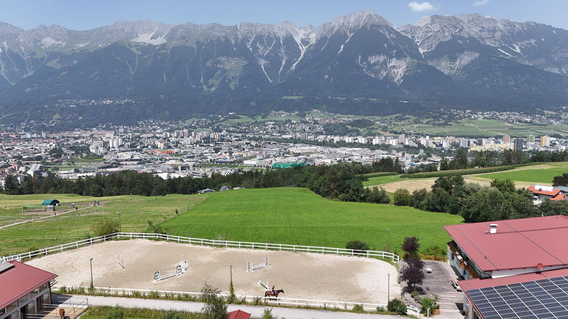 Panoramablick aus der Luft auf das Reitsportzentrum mit Reitplatz, Gebäuden und der Stadt im Tal.