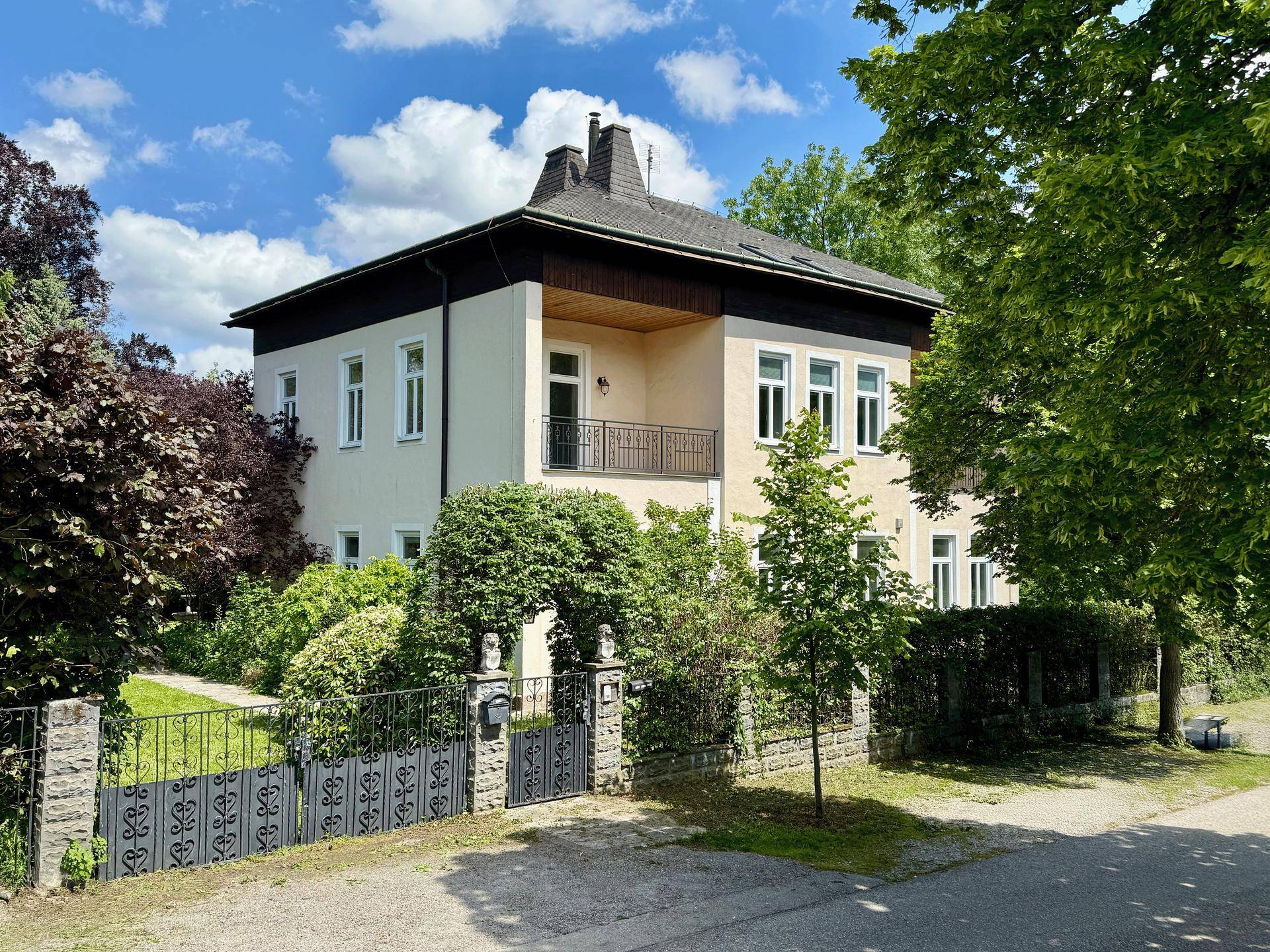 Klassisches Wohnhaus mit gepflegtem Vorgarten, Balkon und schmiedeeisernem Tor.