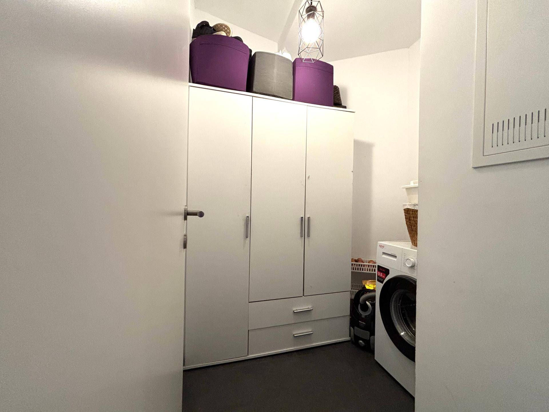 Praktischer Hauswirtschaftsraum mit Waschmaschine, Trockner und integrierten Schränken.