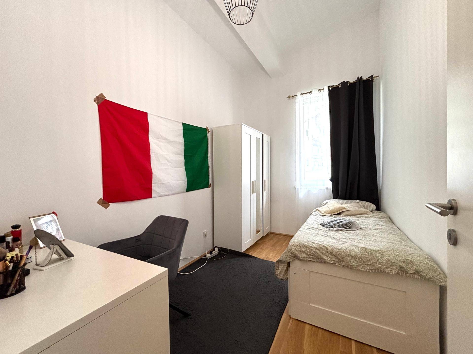 Kinder- oder Gästezimmer mit Einzelbett, Schreibtisch und italienischer Flagge an der Wand.
