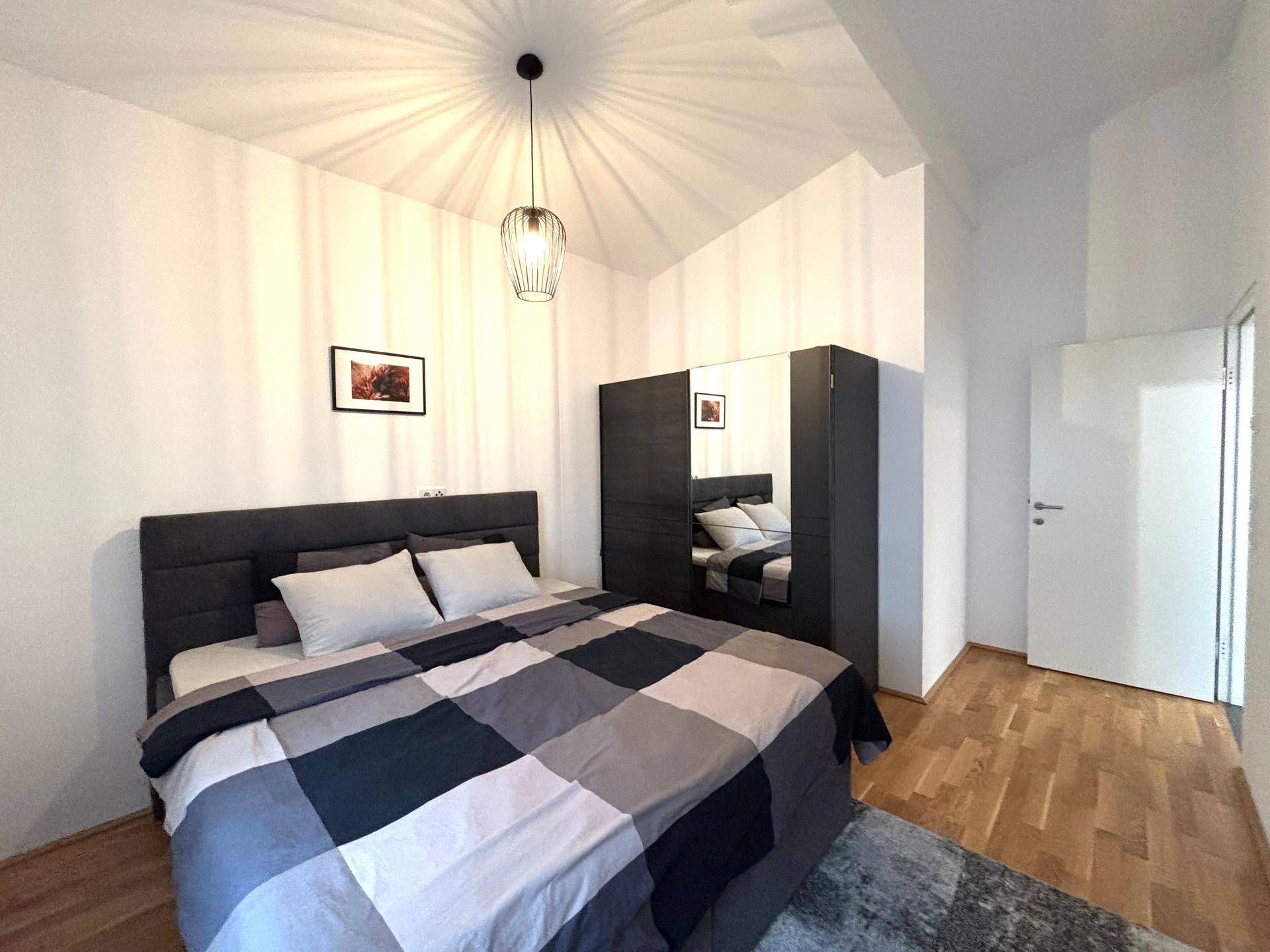 Gemütliches Schlafzimmer mit großem Bett, Kleiderschrank und Holzboden.