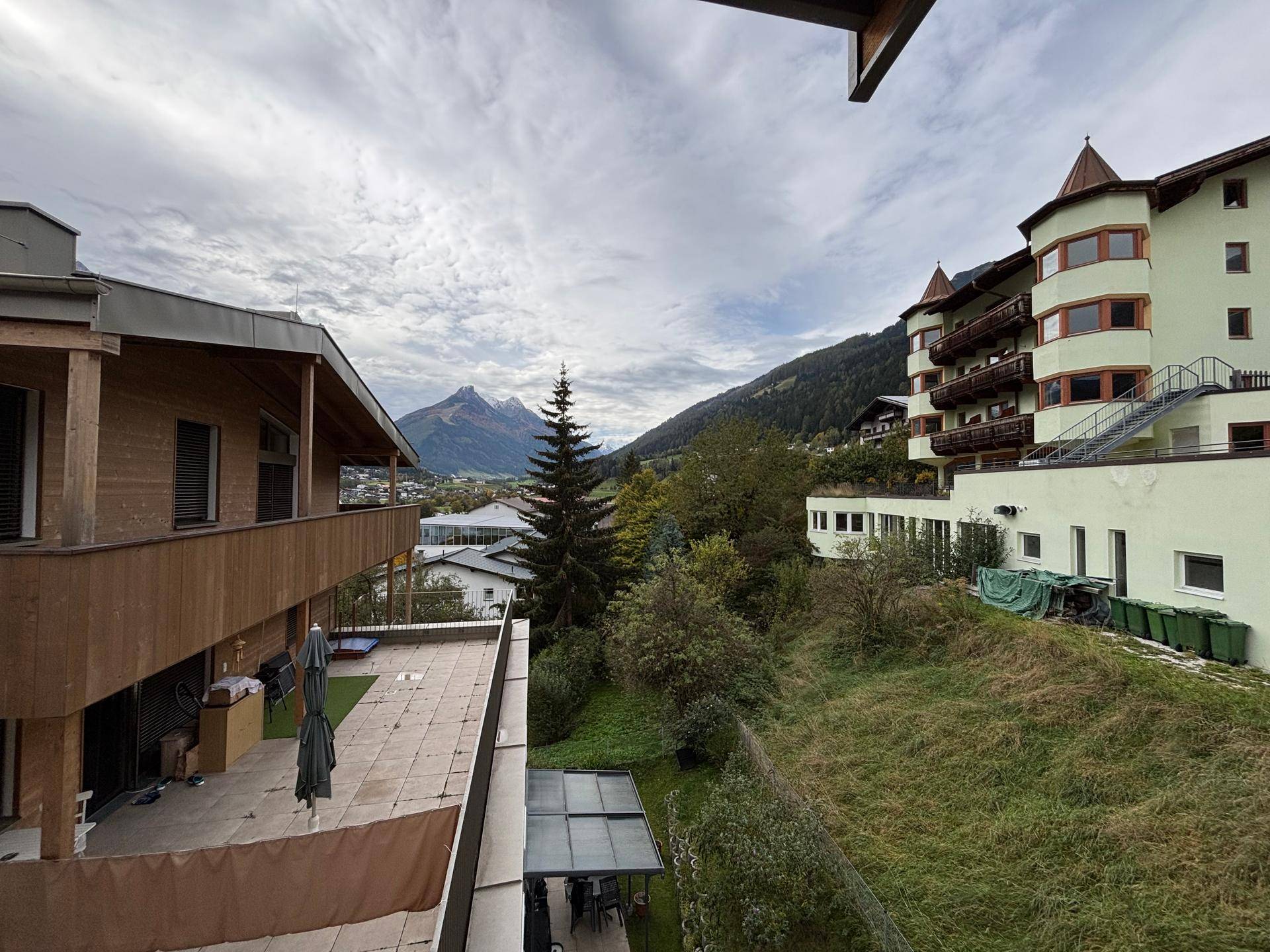 Panoramablick auf die umliegende Berglandschaft und angrenzende Gebäude unter bewölktem Himmel.