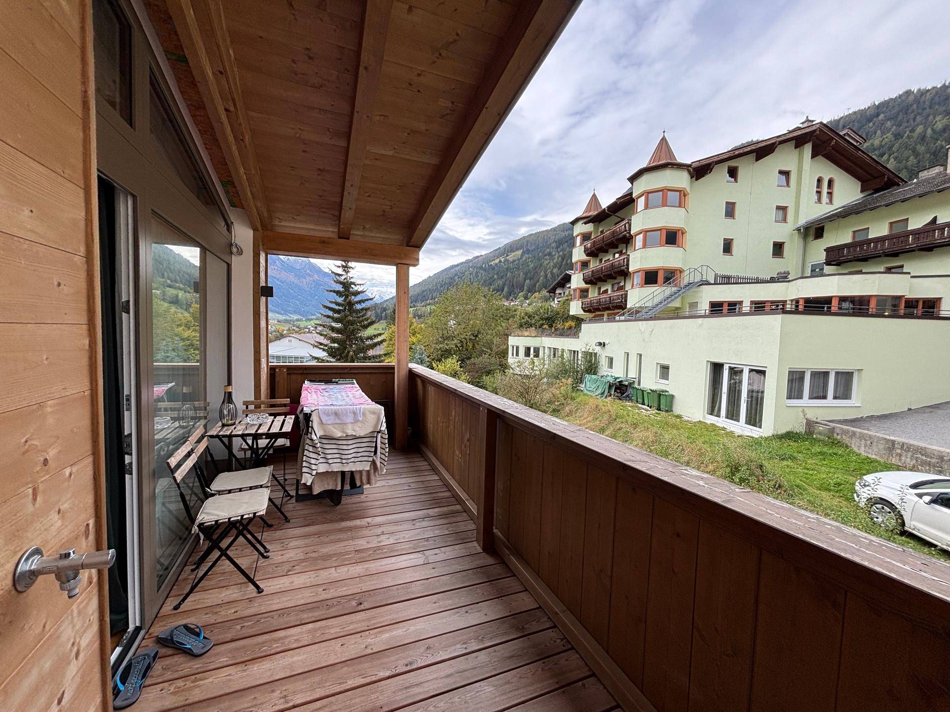 Geräumiger Holzbalkon mit Sitzgelegenheiten und weitem Blick auf die Berge.