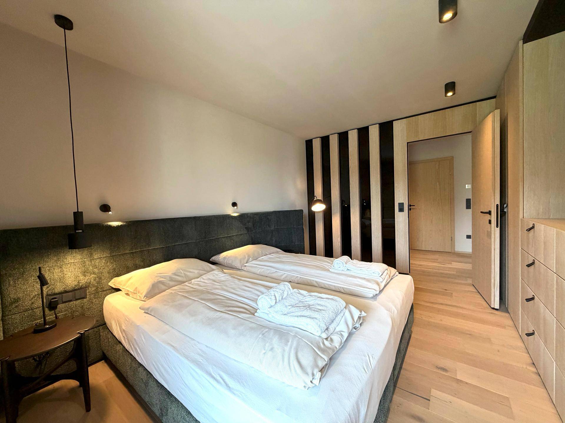 Modernes Schlafzimmer mit Holzboden, bequemen Betten und stilvoller Beleuchtung.