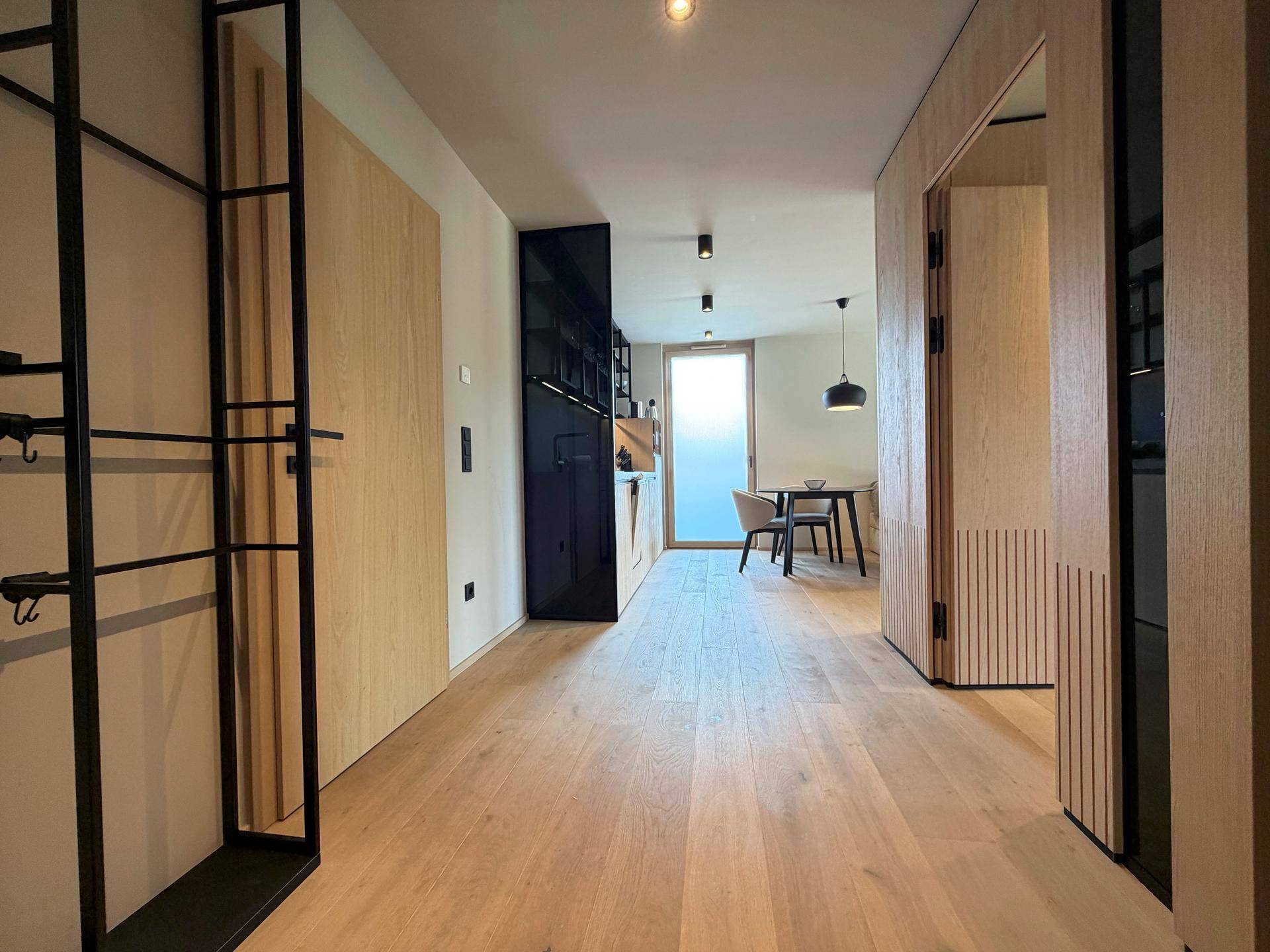 Heller Flur mit Holzboden und modernen Holzwänden, der zum Wohnbereich führt.