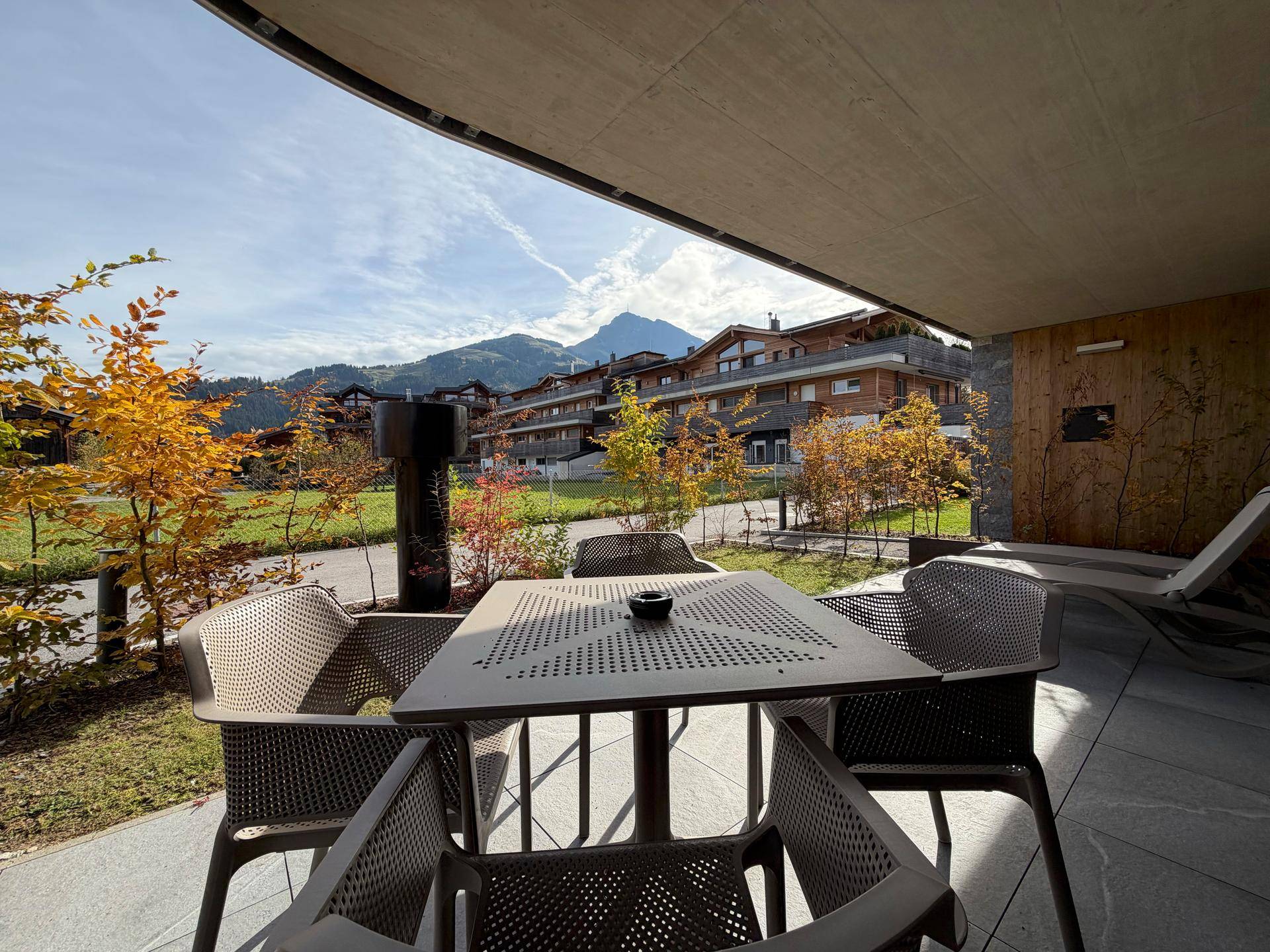 Sonniger Terrassenbereich mit Esstisch, Stühlen und Panoramablick auf die Berge.