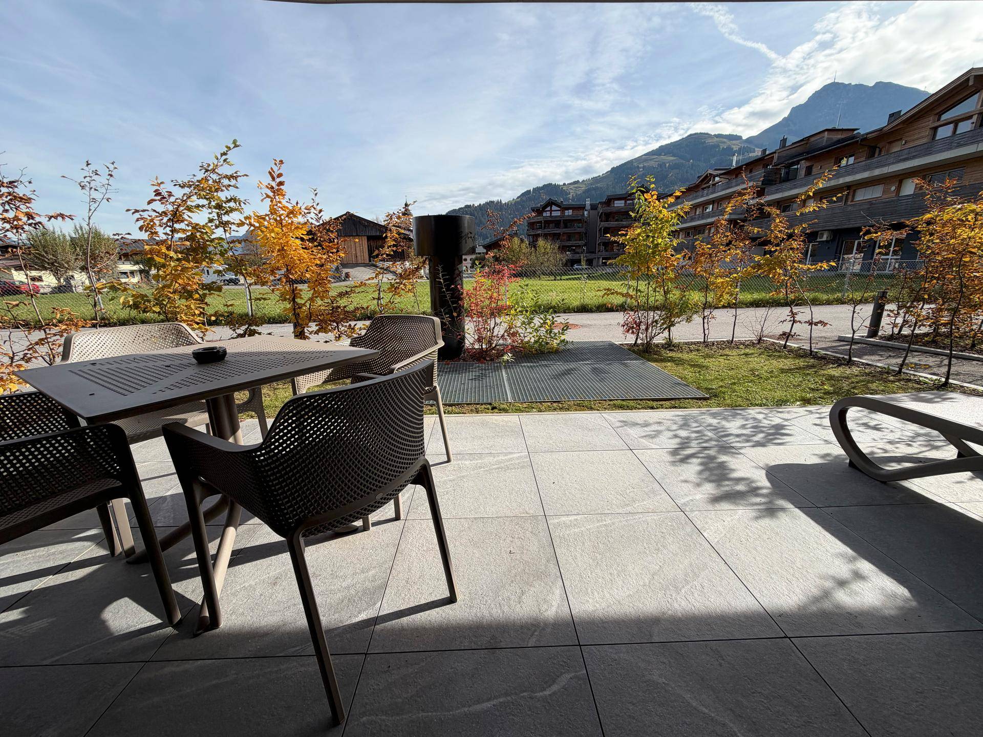 Geräumige Terrasse mit Fliesenboden, Gartenmöbeln und freiem Blick auf die Natur.