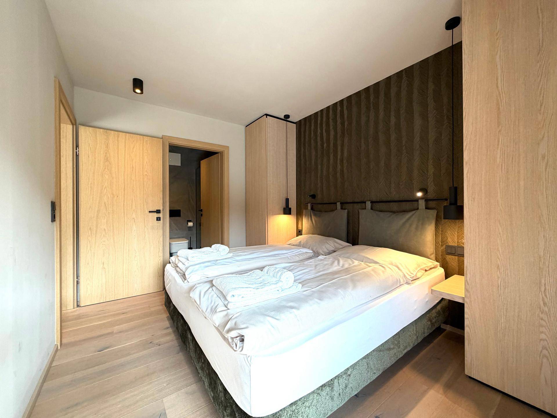 Helles Schlafzimmer mit Holzboden und Zugang zu einem modernen Ensuite-Badezimmer.