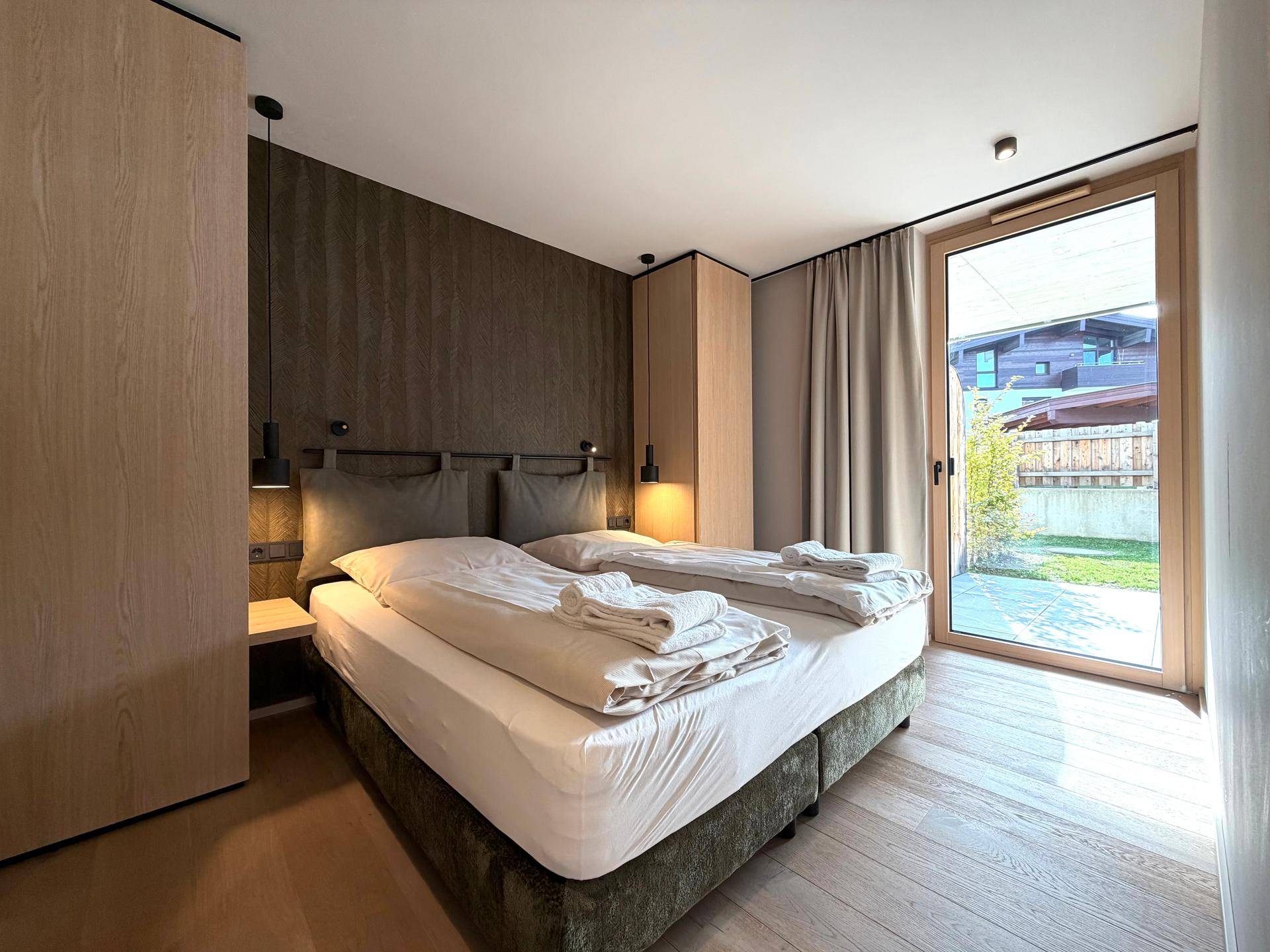 Komfortables Schlafzimmer mit Doppelbett, Holzboden und direktem Zugang zur Terrasse.