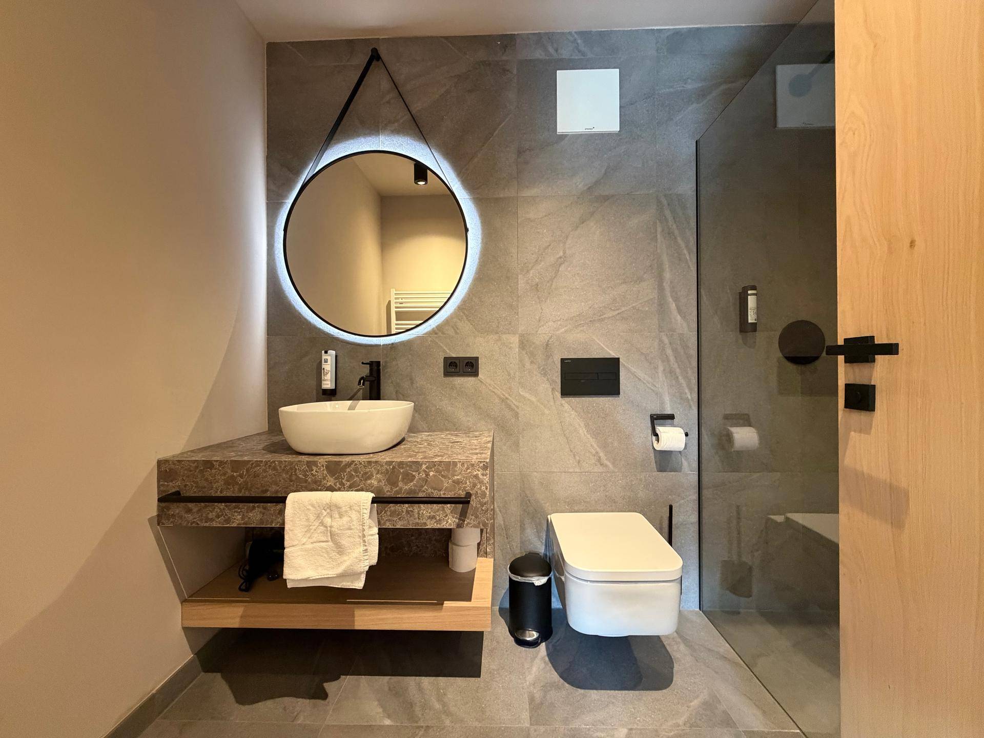 Elegantes Badezimmer mit runden Spiegeln, modernem Waschtisch und ebenerdiger Dusche.