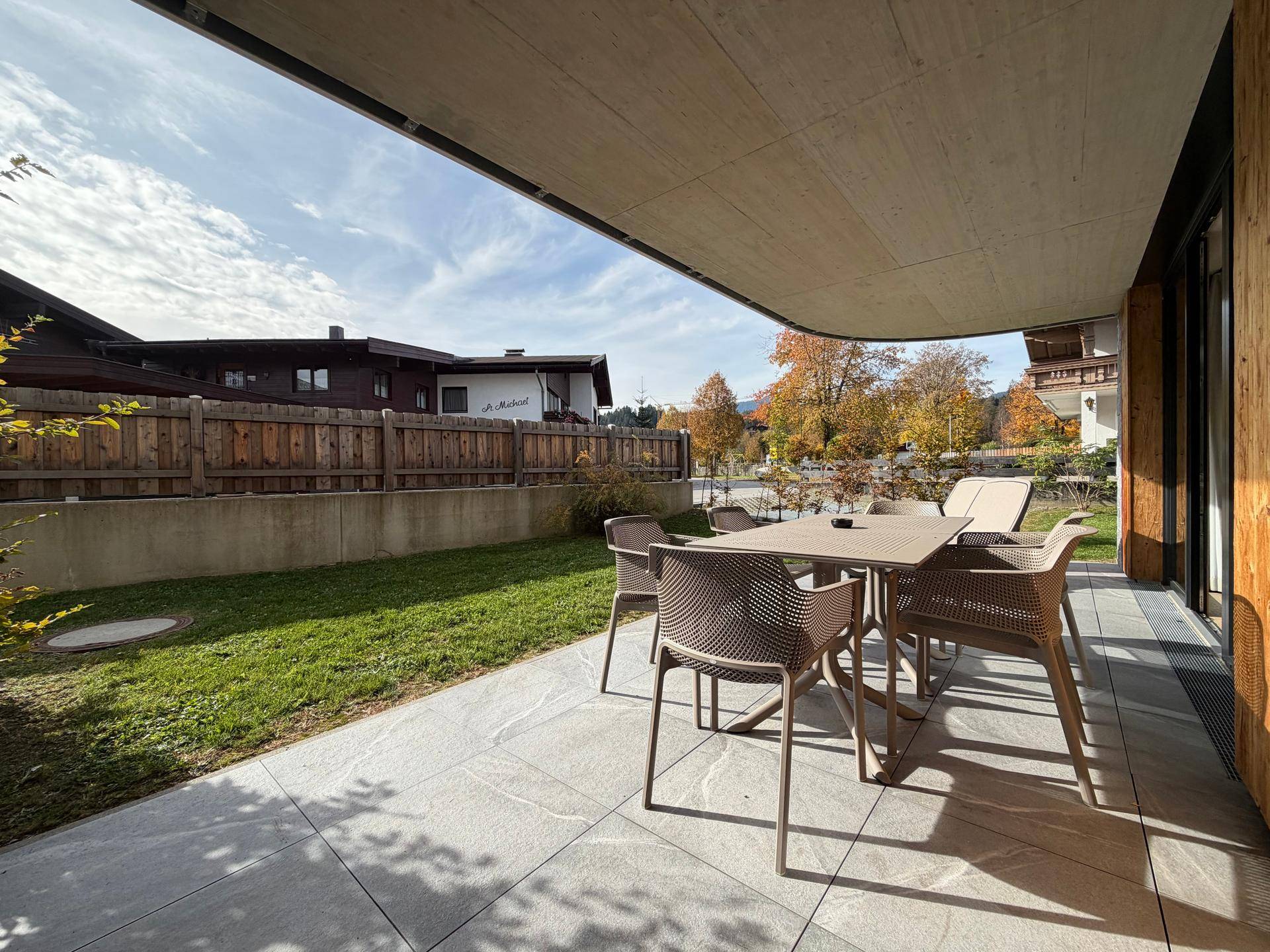 Sonniger Terrassenbereich mit Esstisch und Stühlen, ideal für Mahlzeiten im Freien.