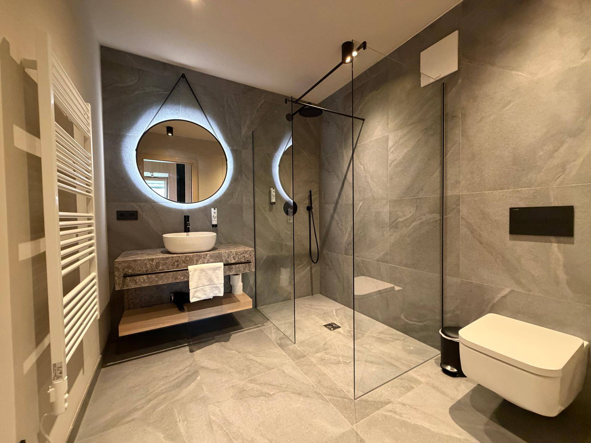 Modernes Badezimmer mit begehbarer Dusche, Wand-WC und stilvollem Waschtisch.