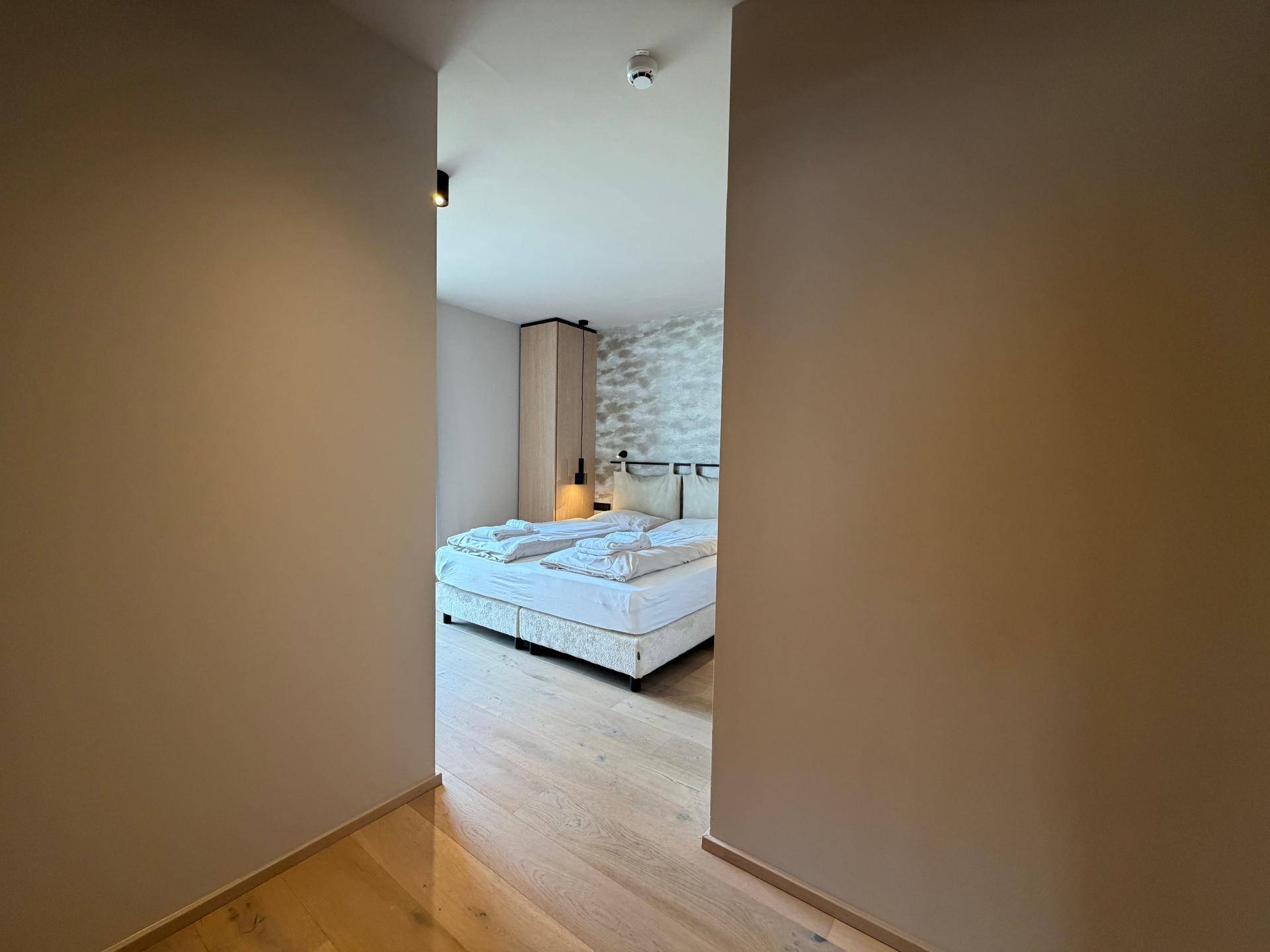 Blick in ein helles Schlafzimmer mit Doppelbett und Holzboden.
