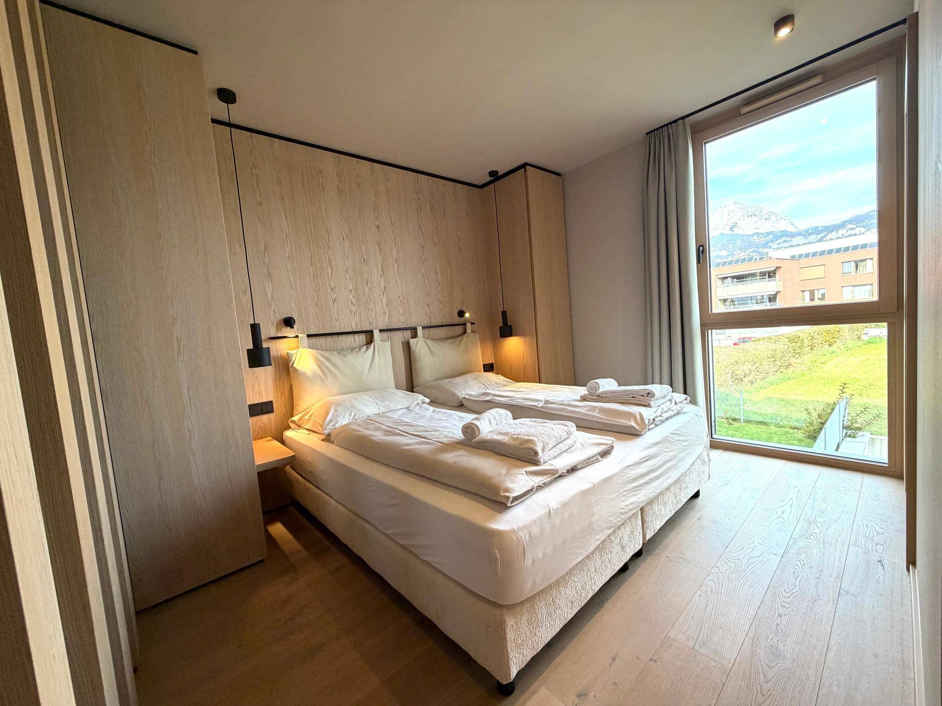 Gemütliches Schlafzimmer mit Doppelbett, Holzelementen und großem Fenster mit Ausblick.