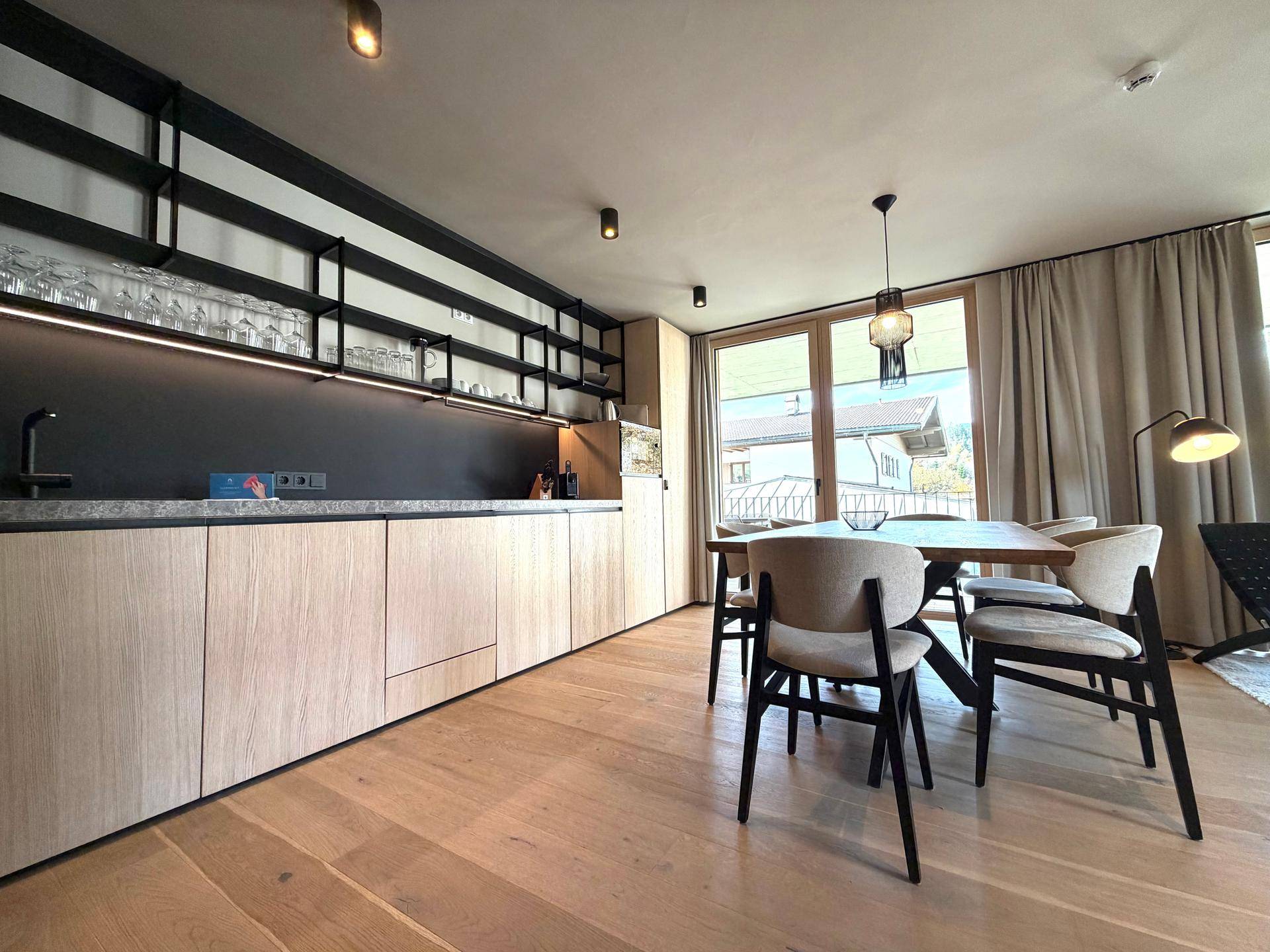 Moderne Einbauküche mit Holzfronten, dunkler Arbeitsplatte und offenen Regalen.
