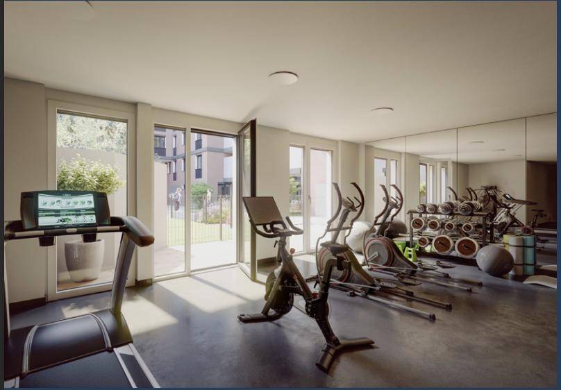 Heller Fitnessraum mit verschiedenen Trainingsgeräten und großen Fenstern zum Außenbereich.