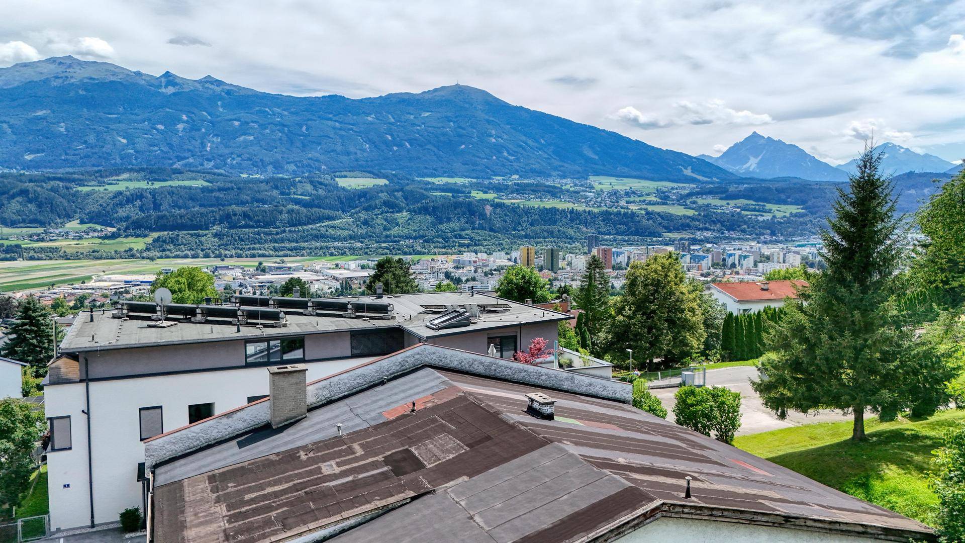 Wohnhausdächer mit Solaranlagen bieten einen weiten Blick auf das Tal und die umliegenden Berge.