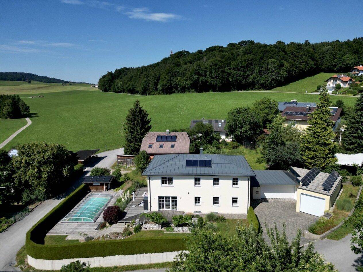 Weitläufige Luftaufnahme des Hauses mit Pool, umgeben von grünen Feldern und Wäldern.