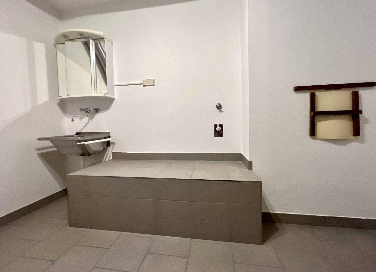 Kellerraum mit Waschbecken und gefliester Ablagefläche, ideal für Hauswirtschaft.