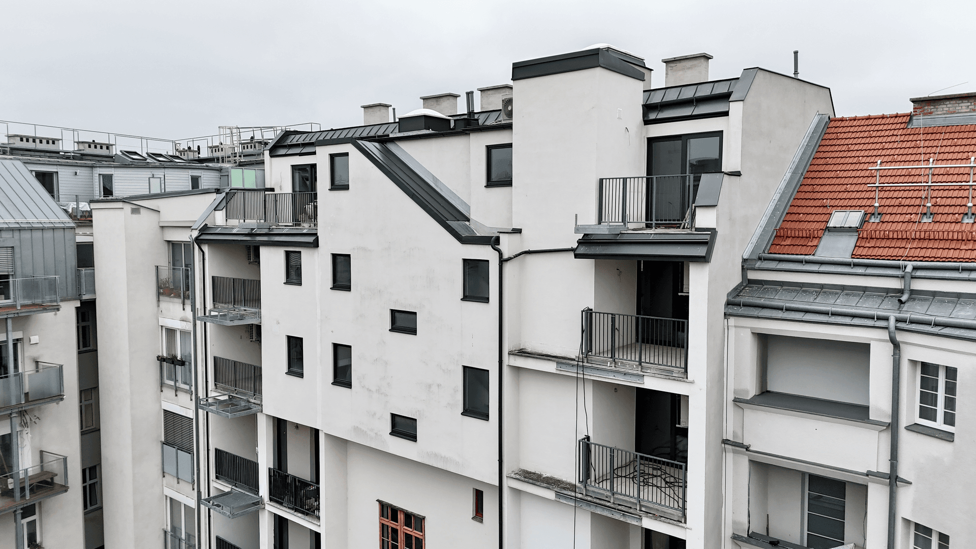 Moderne Architektur eines Neubaus mit verschiedenen Balkonen und Dachformen.