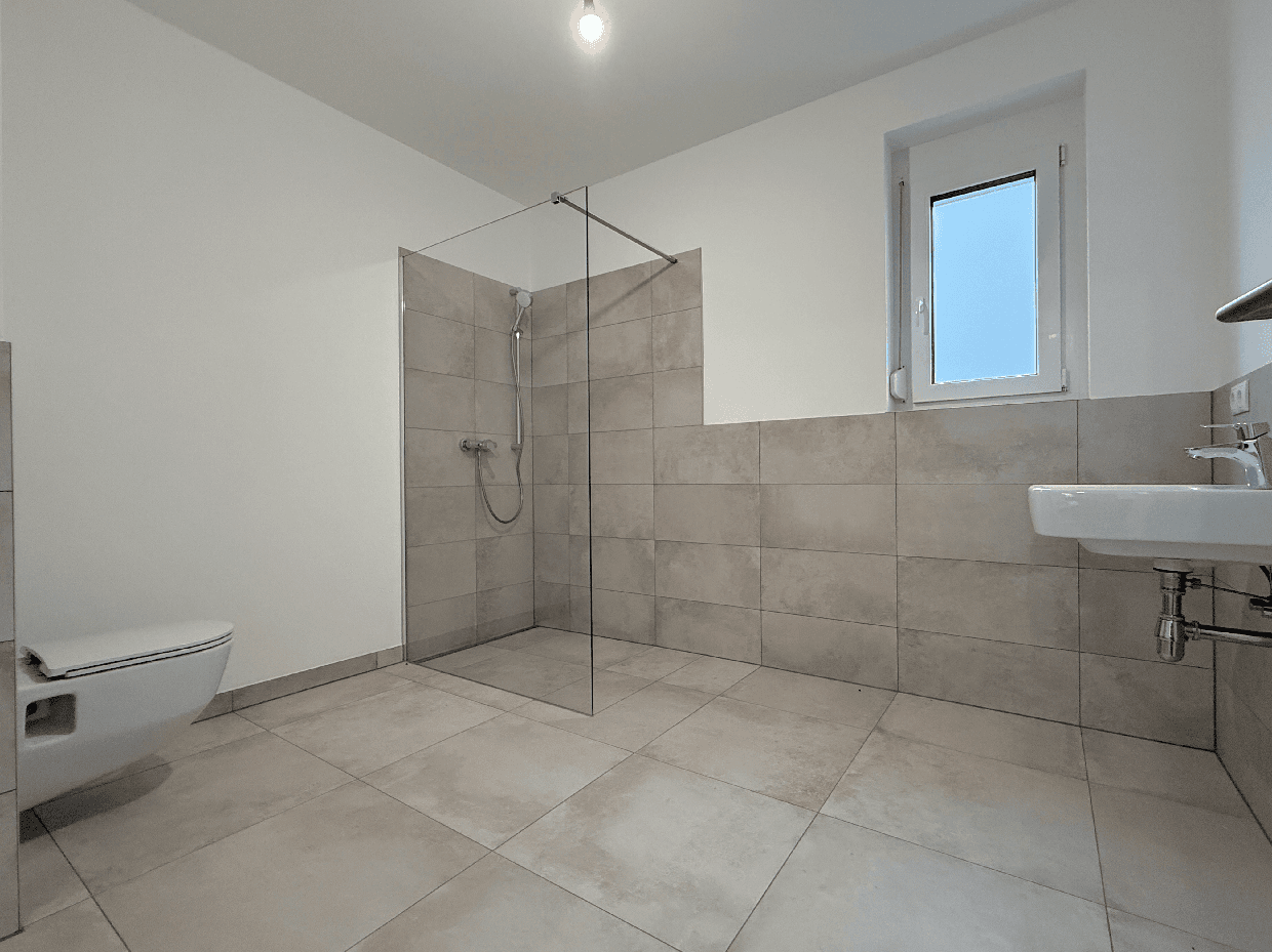 Modernes Badezimmer mit begehbarer Dusche, Wand-WC und Fenster für Tageslicht.
