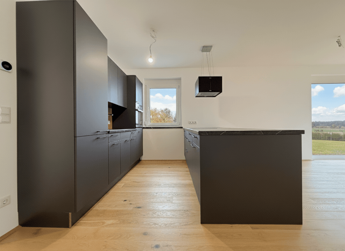 Moderne Einbauküche in dunklen Farbtönen mit Kücheninsel und hochwertigen Geräten.