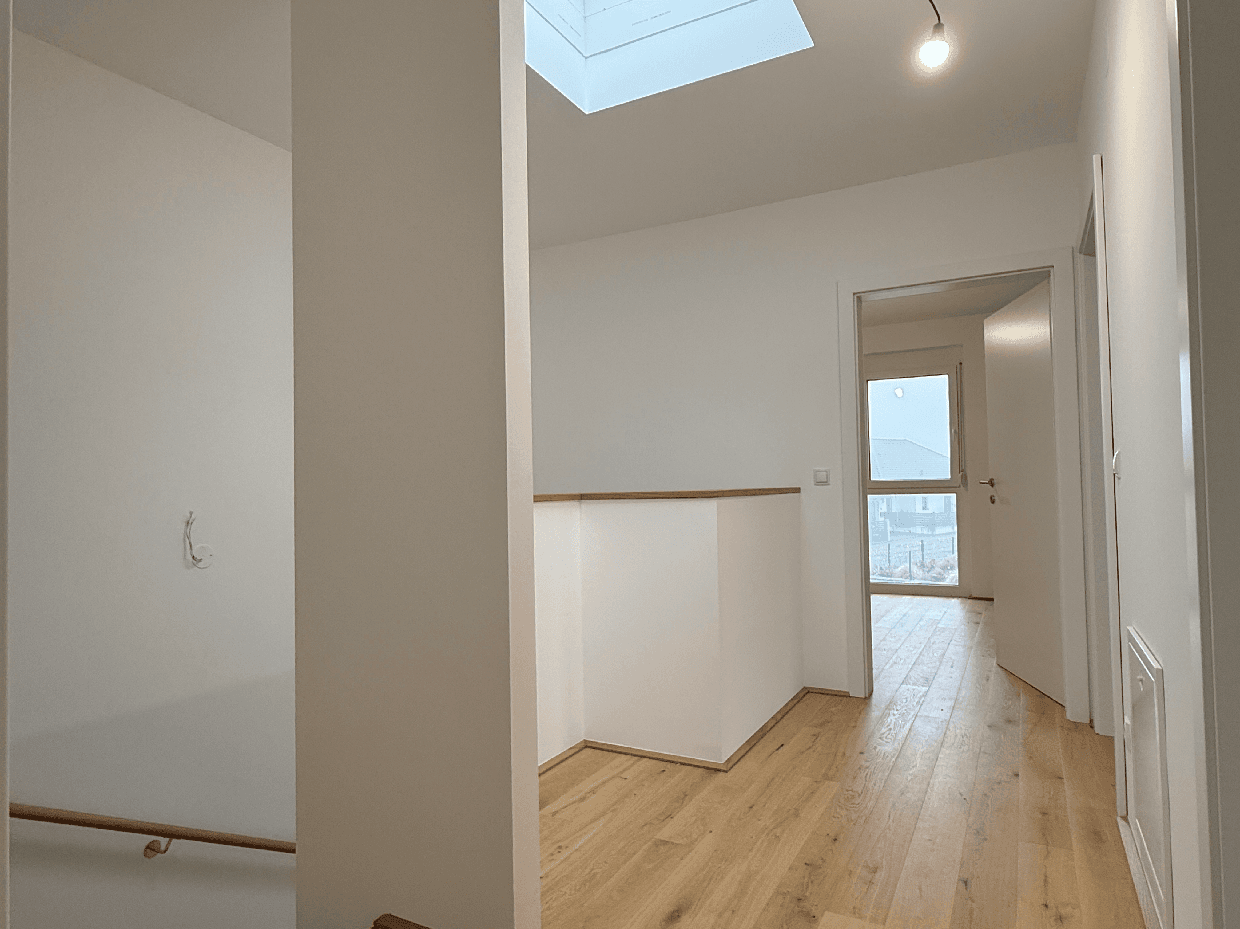 Heller Flur mit Holzboden, Oberlicht und Zugang zu weiteren Räumen.