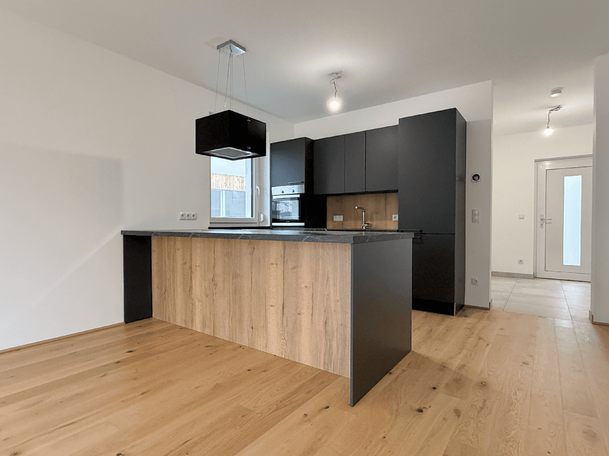 Moderne Einbauküche mit dunklen Fronten, Kücheninsel und integrierten Geräten.