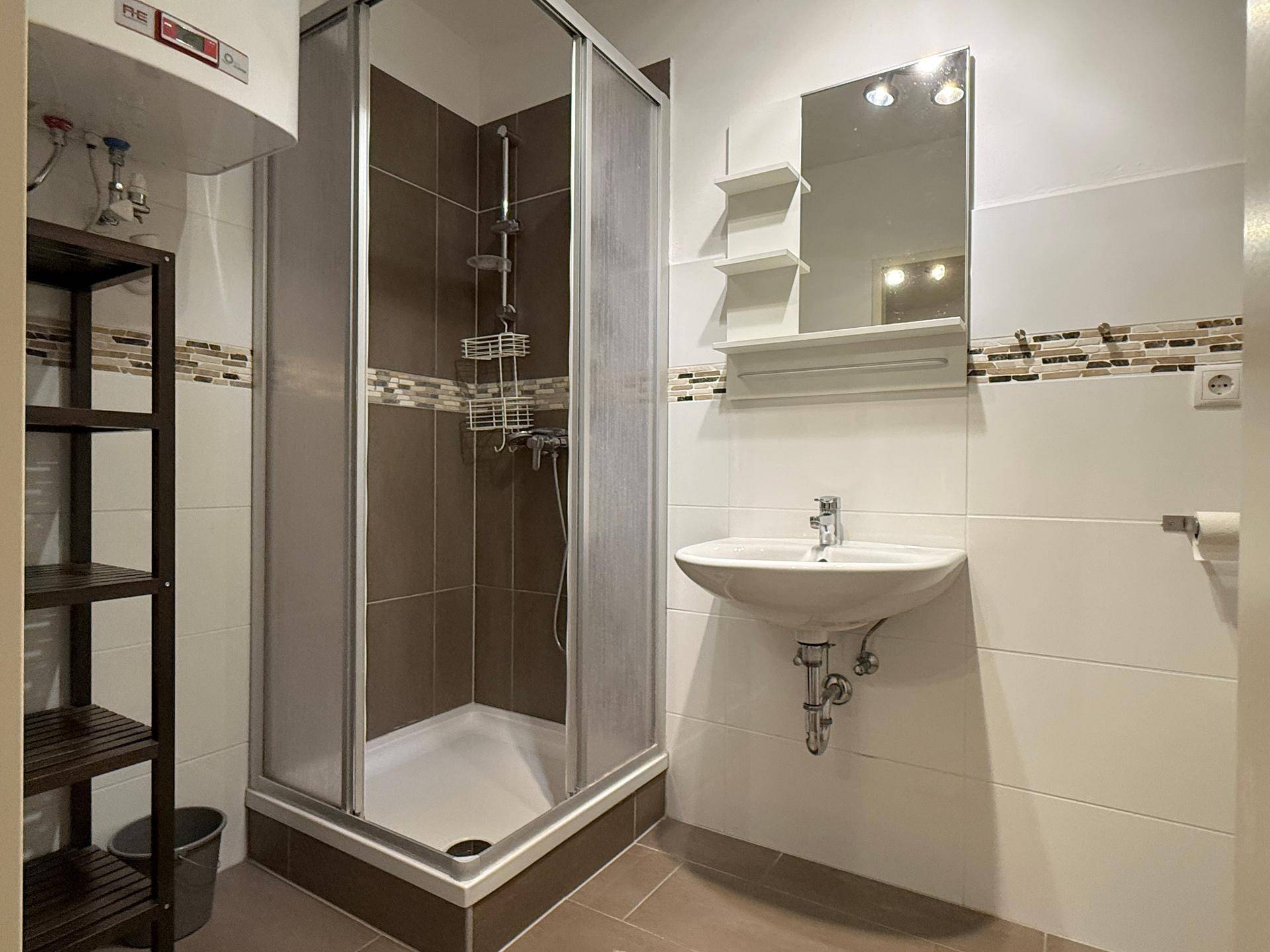 Modernes Badezimmer mit Duschkabine, Waschbecken und Wandspiegel in neutralen Farbtönen.