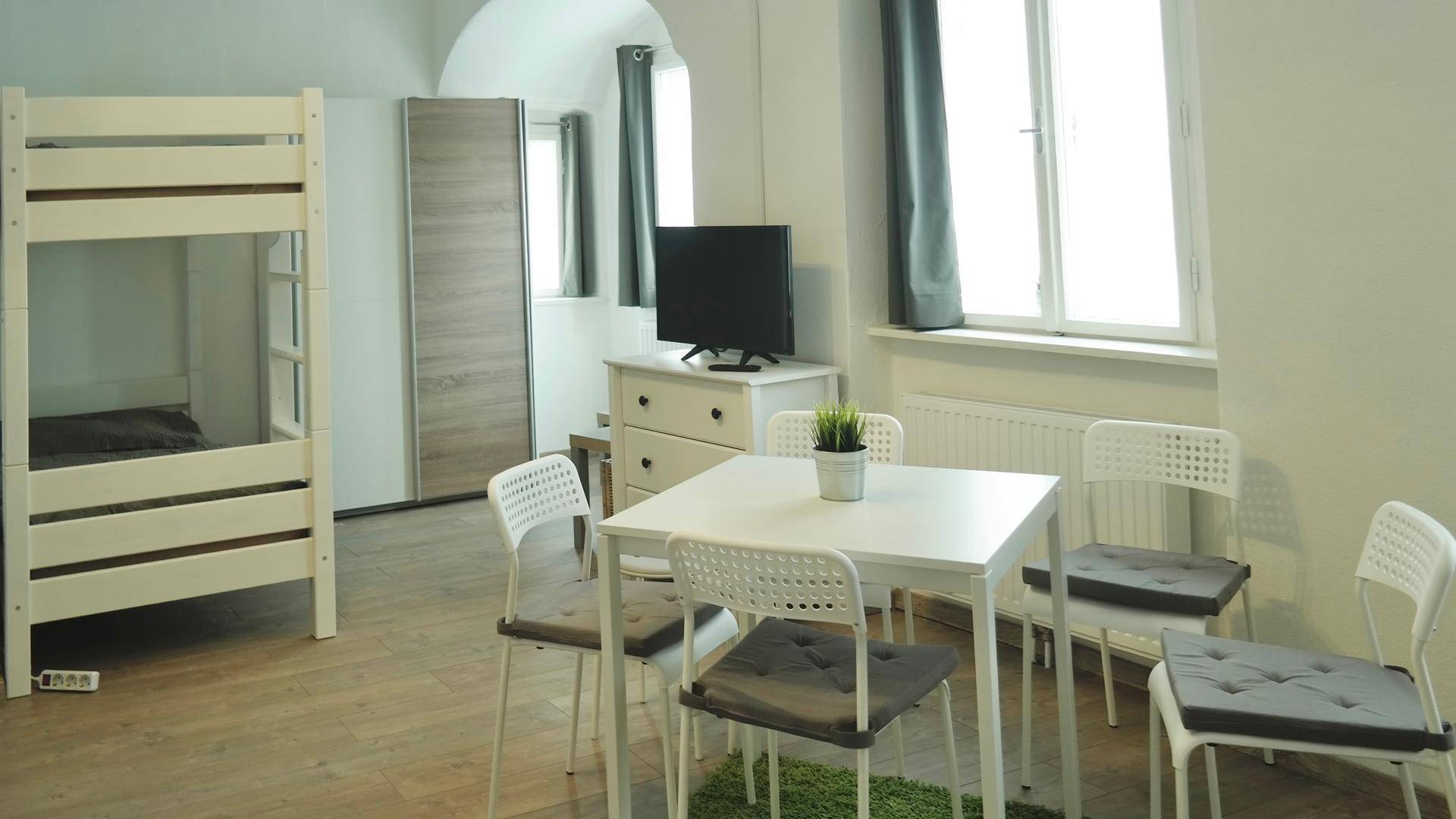 Helles Schlafzimmer mit Etagenbett, Esstisch und Fernseher, ideal für Gäste oder Familien.