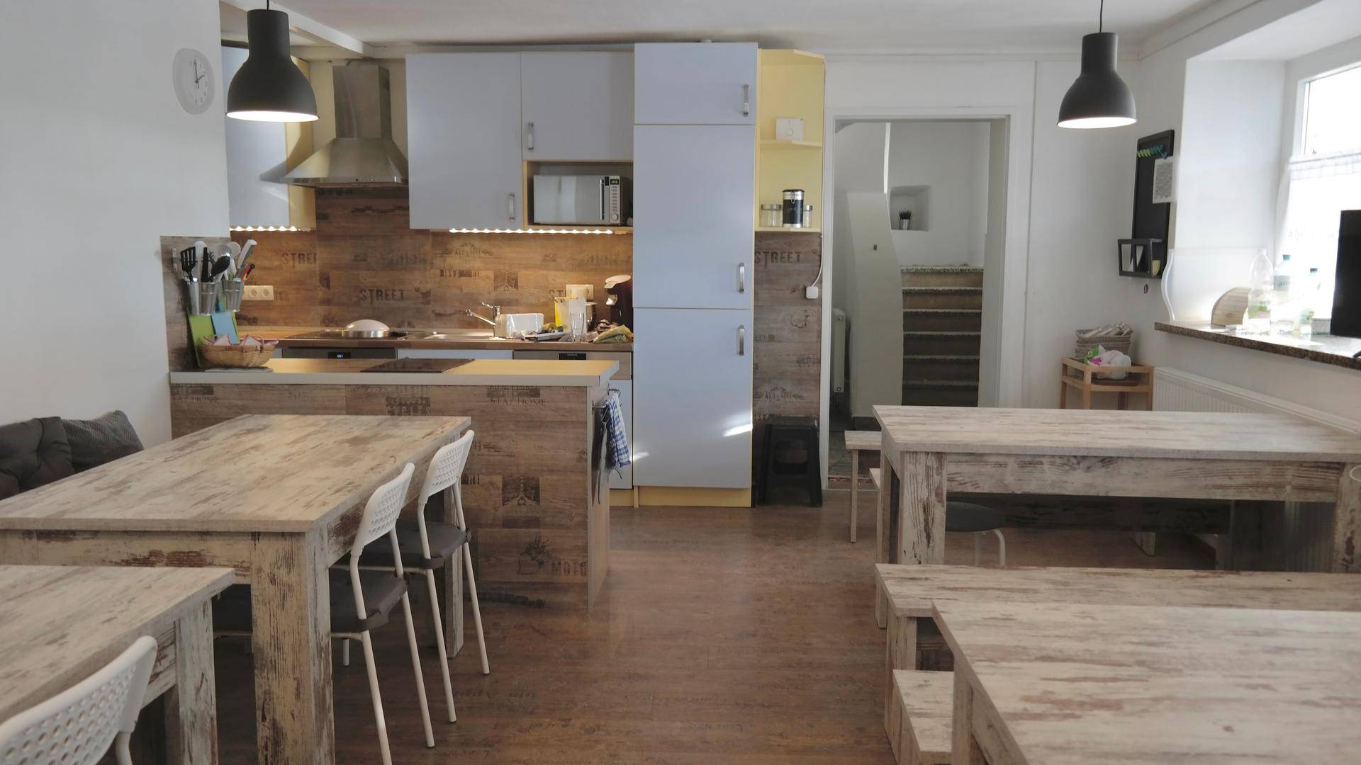 Geräumige Wohnküche mit Holztischen, Küchenzeile und viel Platz für gemeinsame Mahlzeiten.