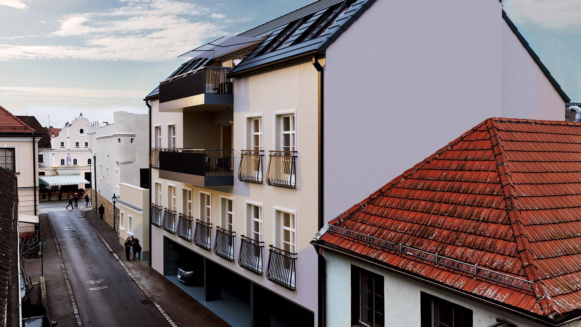 Moderne Gebäudefassade mit Balkonen und großen Fenstern, angrenzend an ein traditionelles Haus mit rotem Ziegeldach.