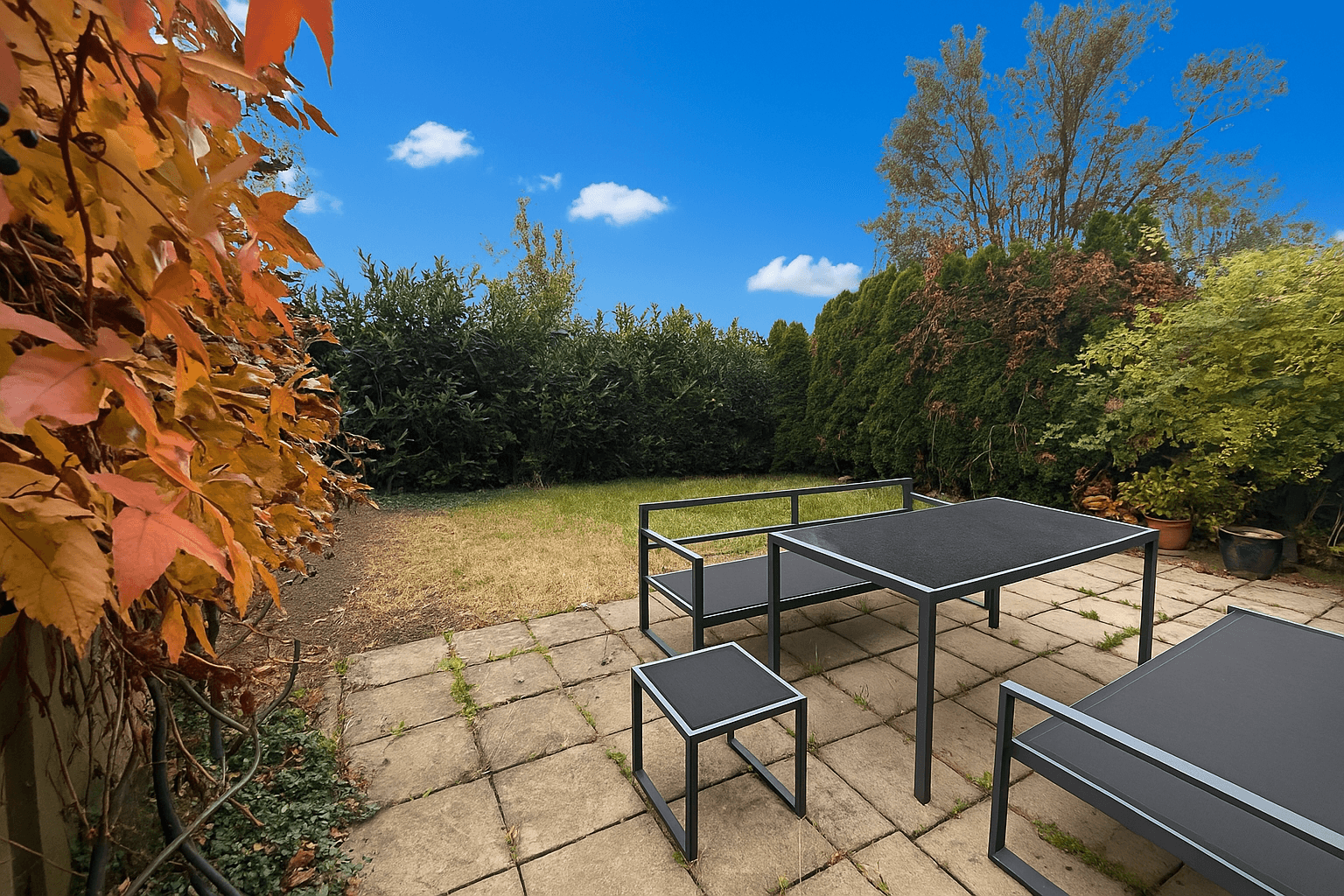 Gepflasterte Terrasse mit modernen Gartenmöbeln und umgebender grüner Hecke im Außenbereich.