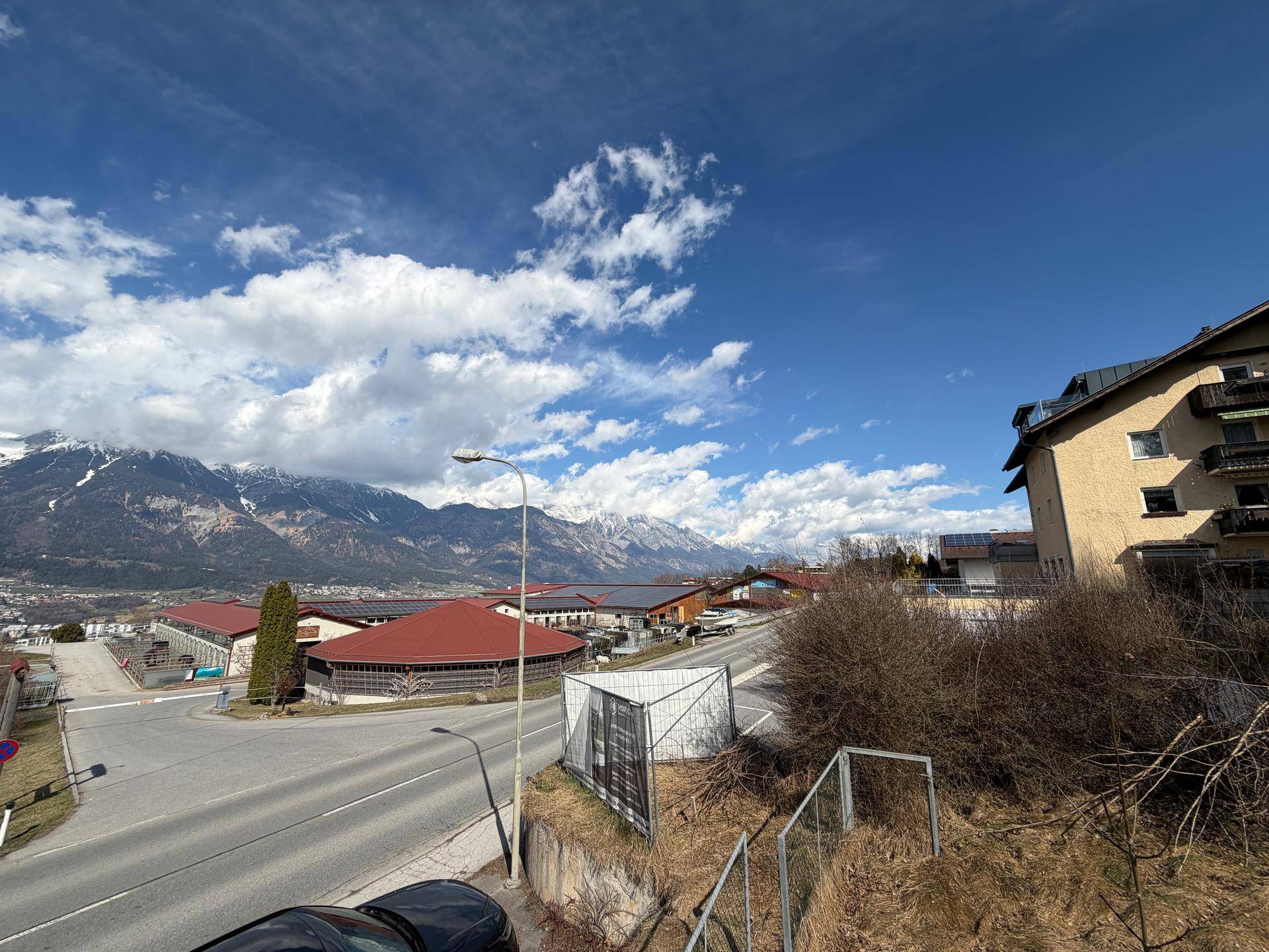 Panoramablick auf die schneebedeckten Berge und die umliegende Bebauung unter blauem Himmel.