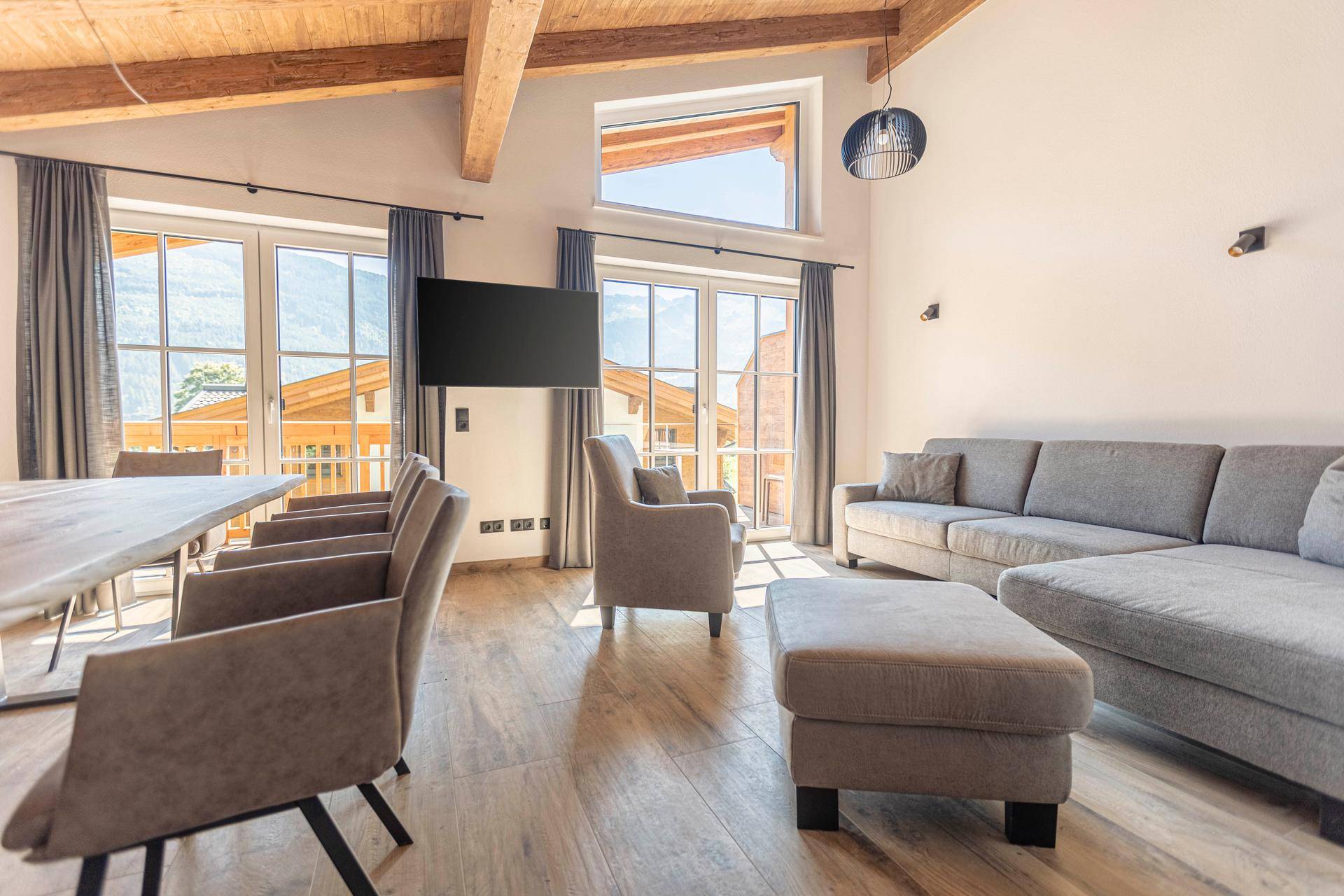 Geräumiger Wohnbereich mit bequemen Sofas, Holzbalkendecke und großen Fenstern mit Bergblick.