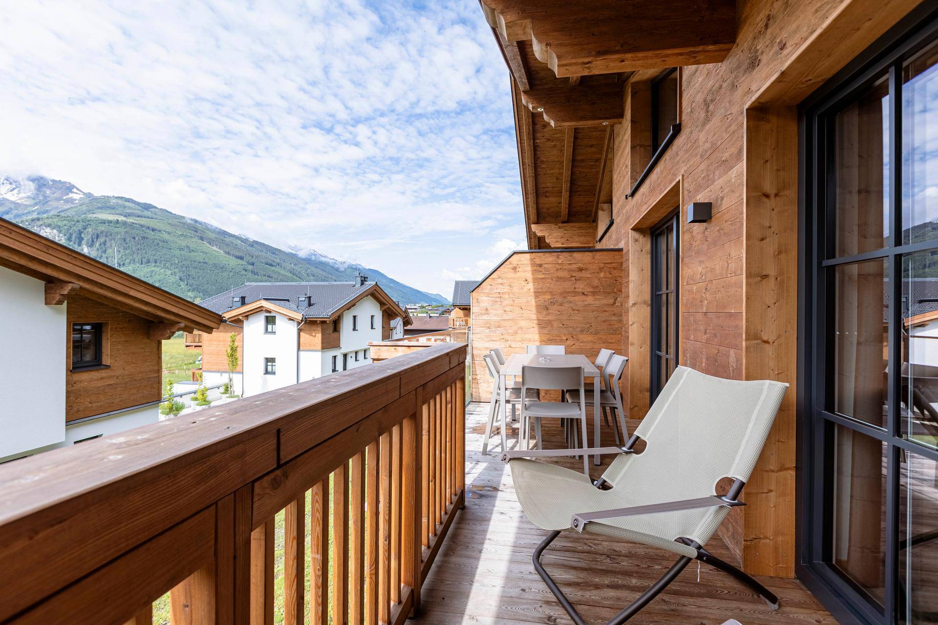 Geräumiger Holzbalkon mit Sitzgelegenheiten und weitem Blick auf die Berglandschaft.
