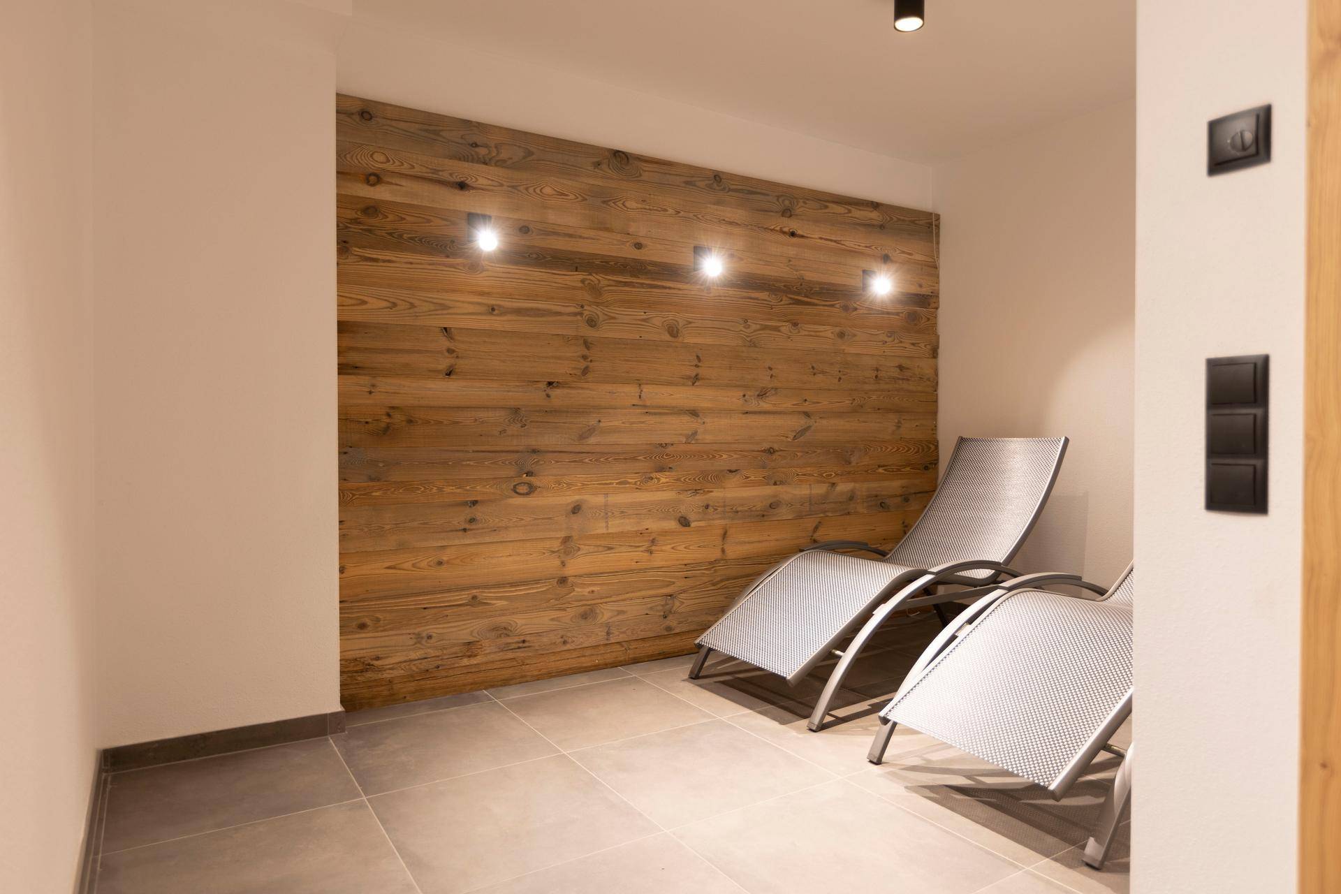 Entspannungsbereich mit Liegestühlen und Holzwandverkleidung, ideal zum Ausruhen nach der Sauna.