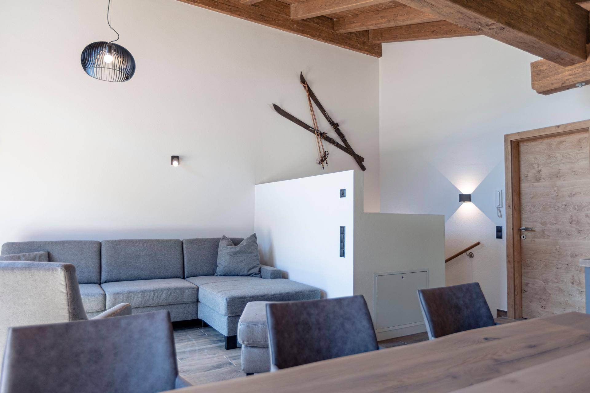 Gemütlicher Wohnbereich mit Ecksofa, Holzbalkendecke und Treppenaufgang im modernen Stil.
