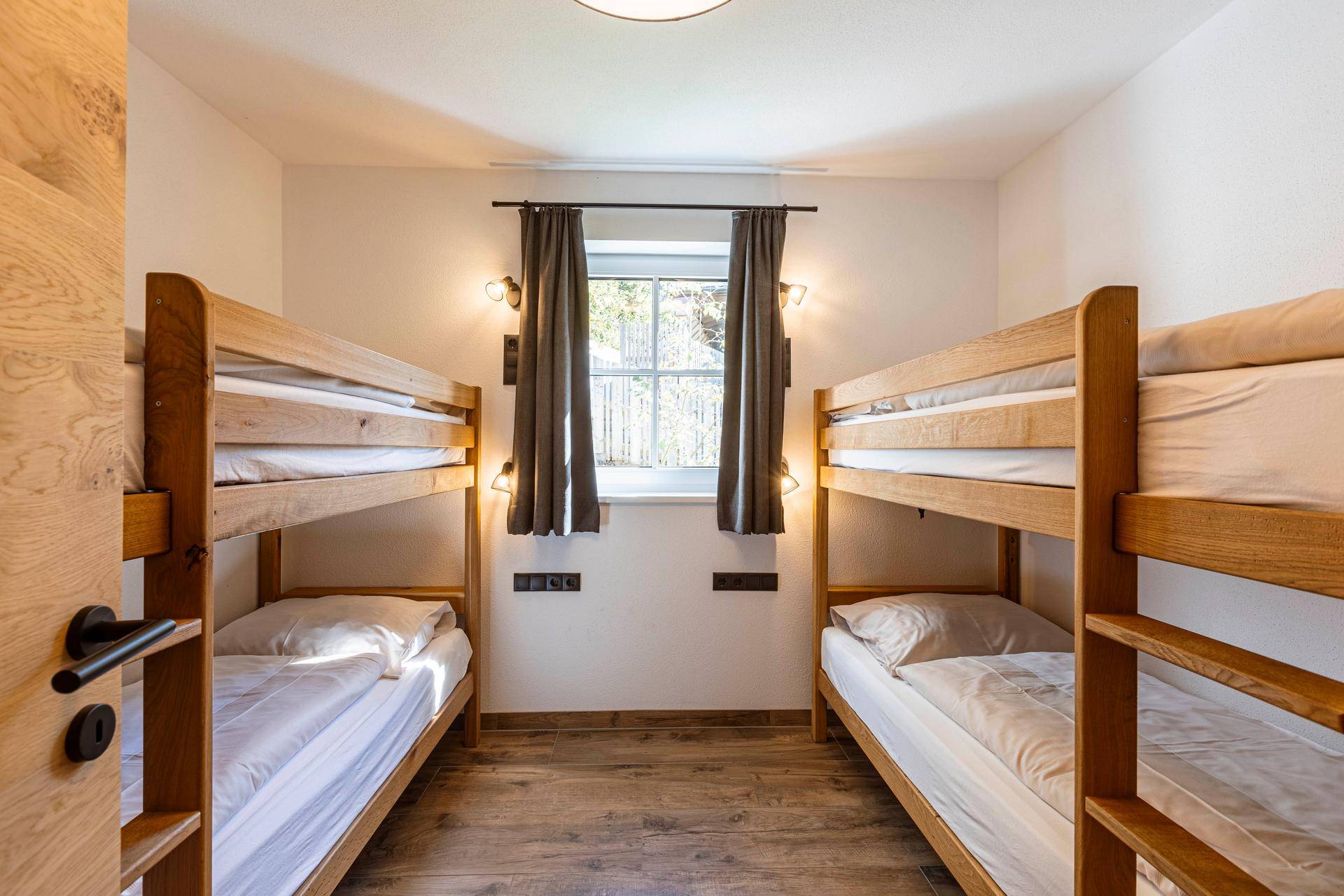 Kinderzimmer mit zwei Etagenbetten, Holzboden und Fenster für natürliche Belichtung.