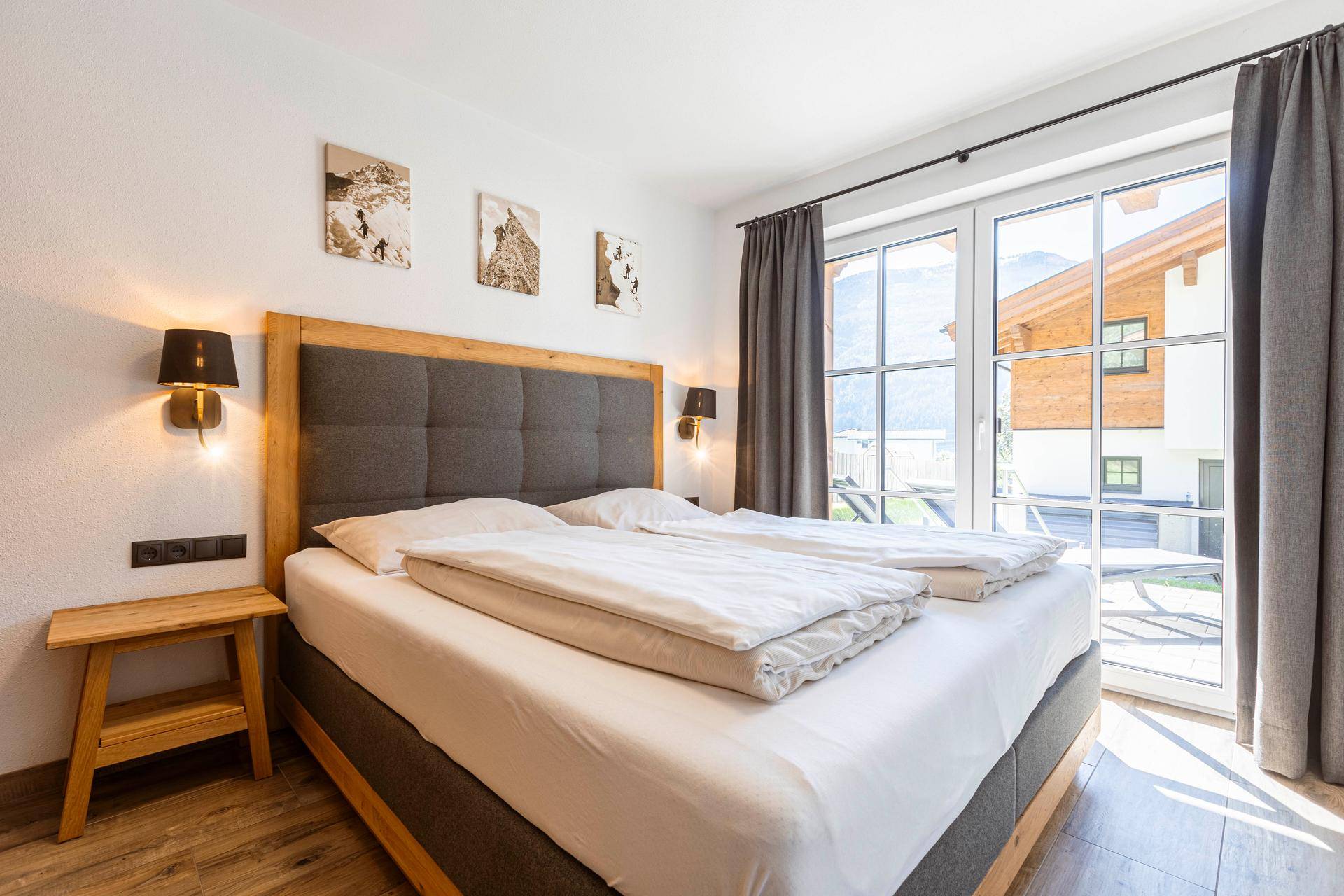 Komfortables Schlafzimmer mit Doppelbett, Holzboden und Blick auf die umliegende Berglandschaft.