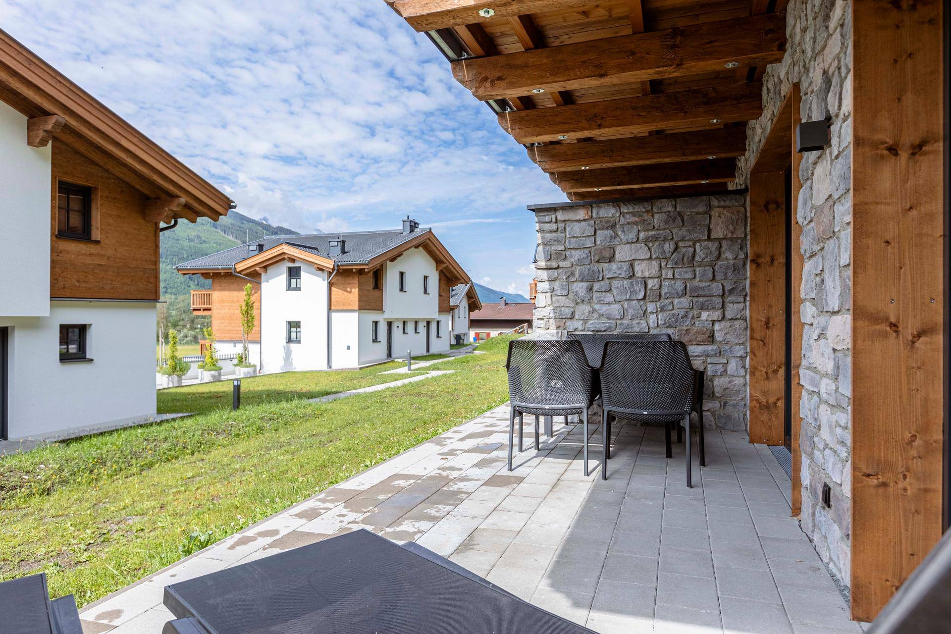 Sonnenterrasse mit Sitzgelegenheiten und Blick auf die umliegenden Häuser und Berge.