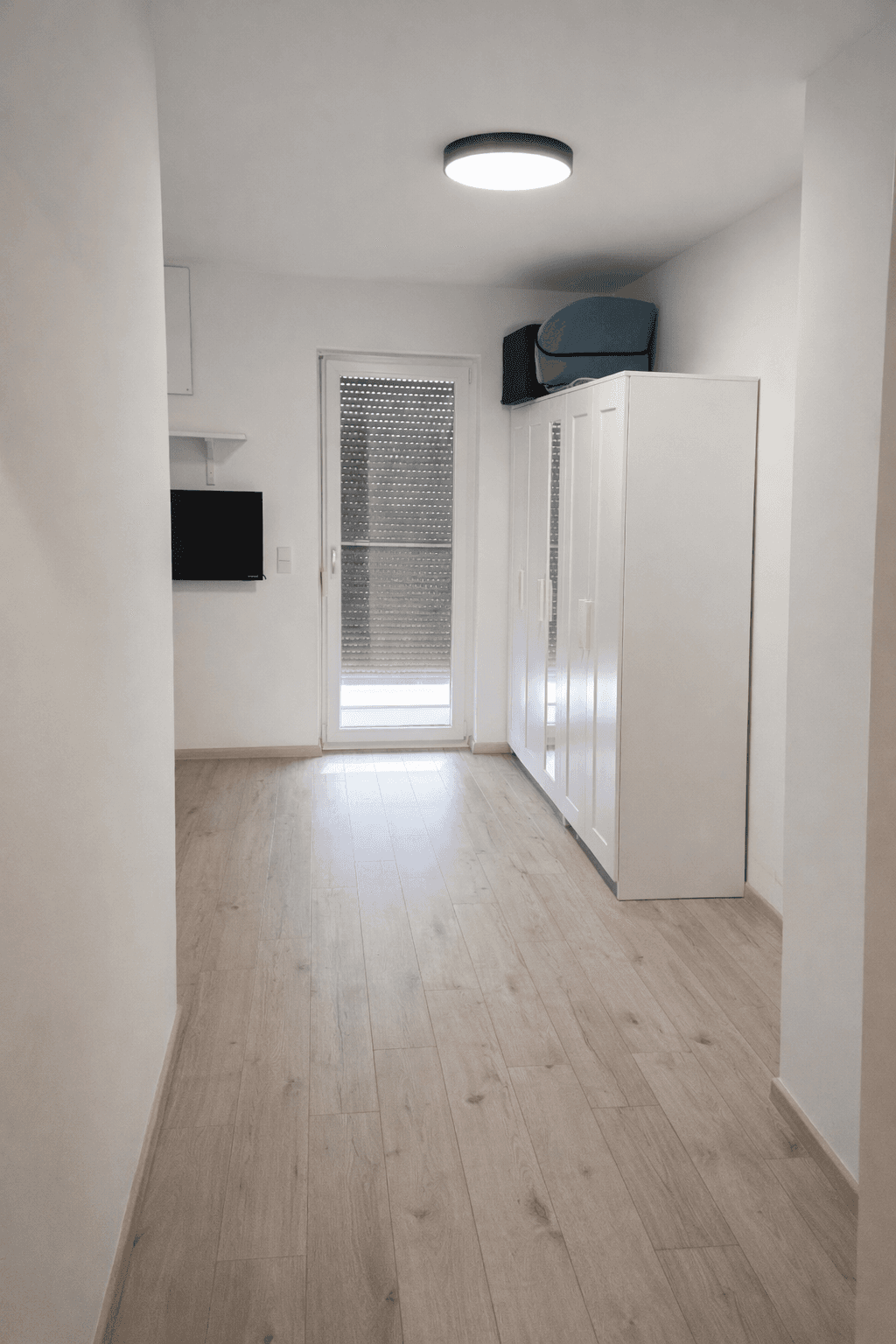 Heller Flur mit Laminatboden und Zugang zu einem Außenbereich.