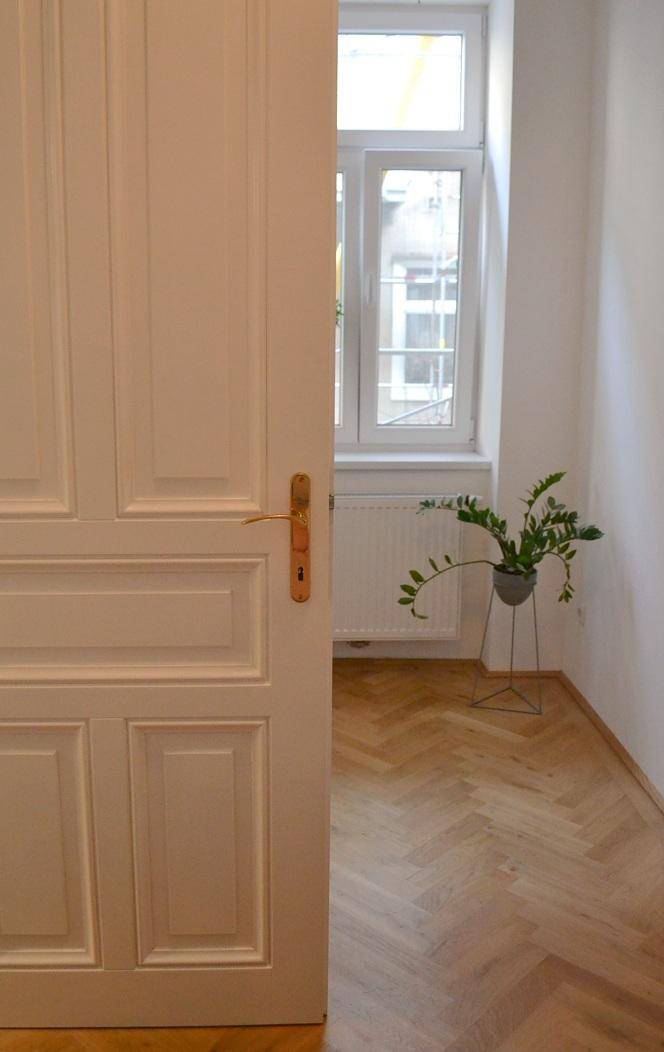 Heller Raum mit Fischgrätparkett und einer weißen Flügeltür.
