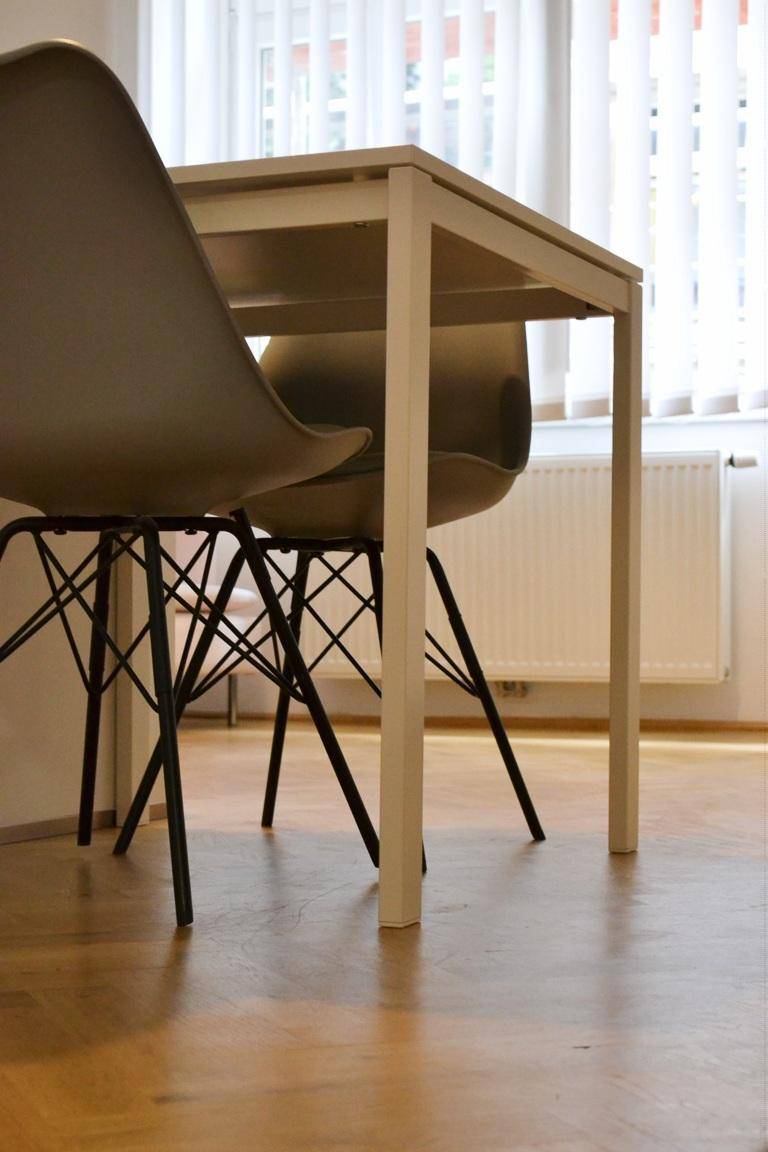 Kleiner Essbereich mit modernem Tisch und Stühlen neben einem Fenster.