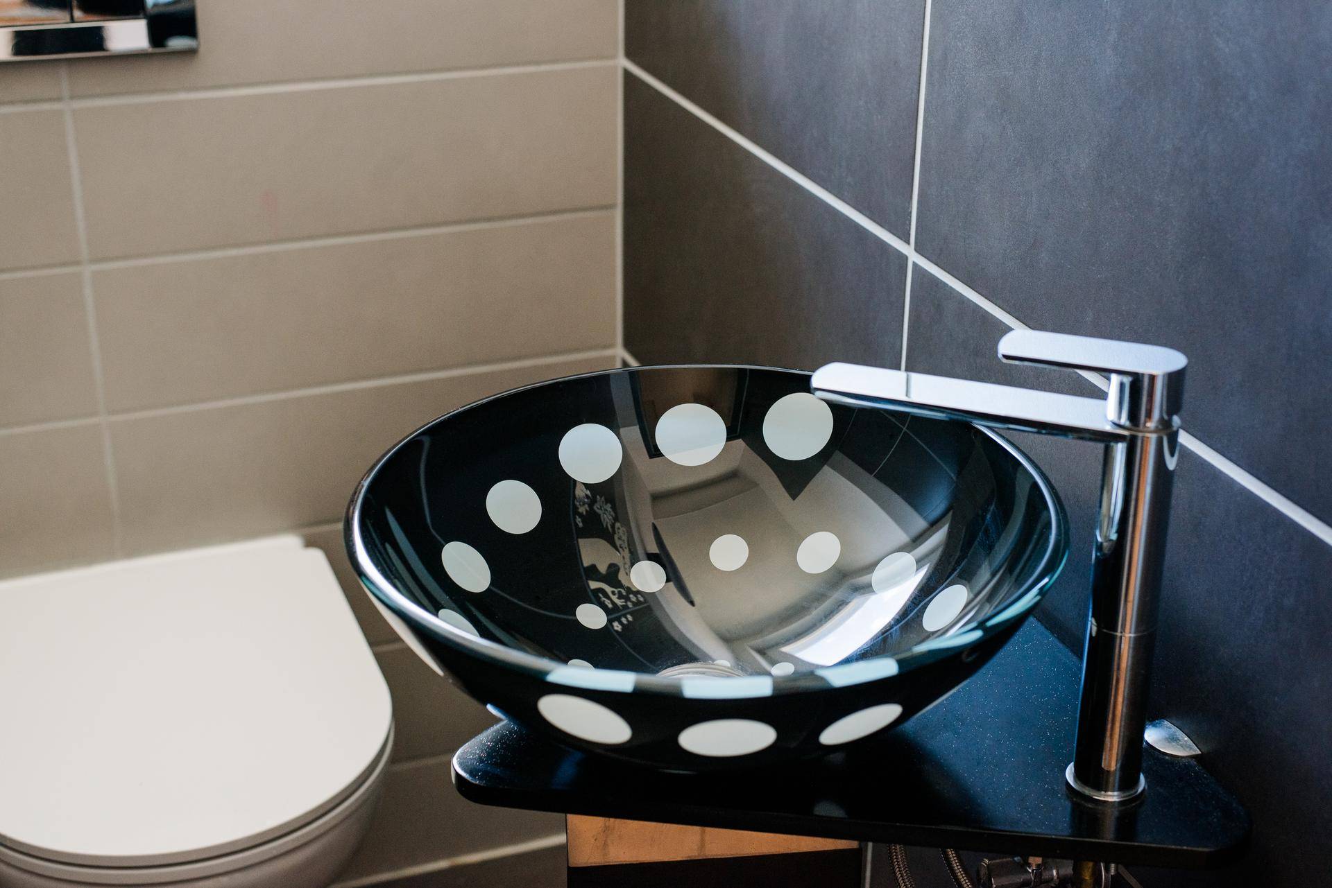Detailaufnahme des einzigartigen schwarzen Waschbeckens mit weißen Punkten im Gäste-WC.