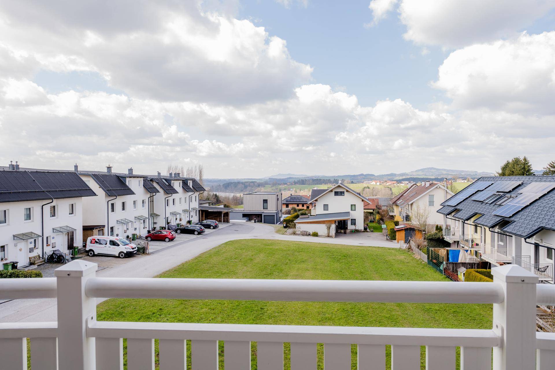 Weitblick vom Balkon über die Nachbarschaft mit Grünflächen und hügeliger Landschaft.